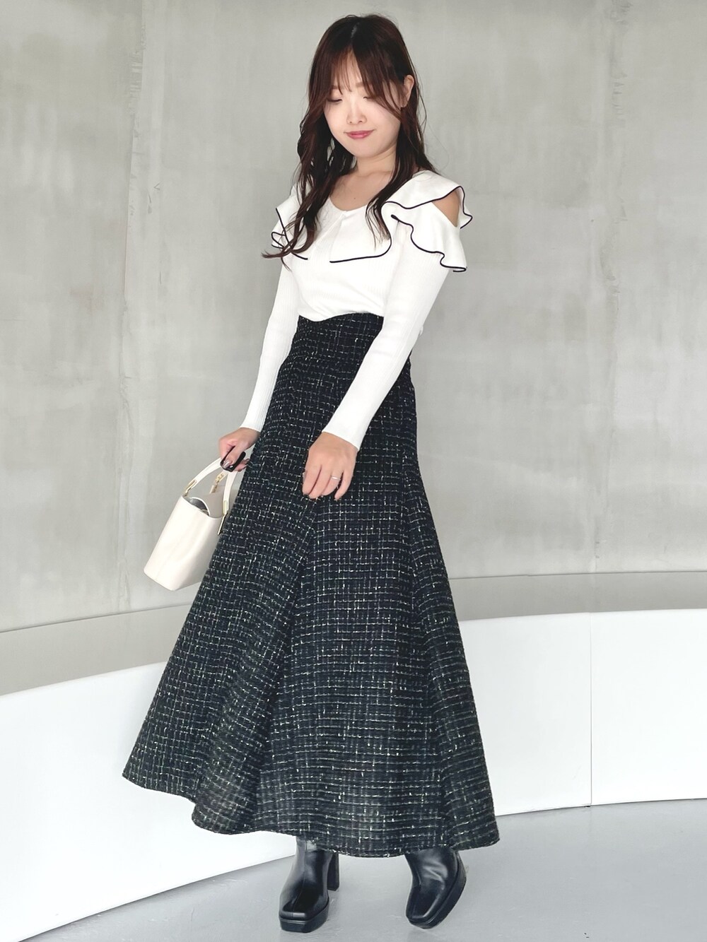 その他のニット/セーター、ブラック系のスカート、ホワイト系のハンドバッグを着用したレディースの秋コーディネートの2枚目の写真