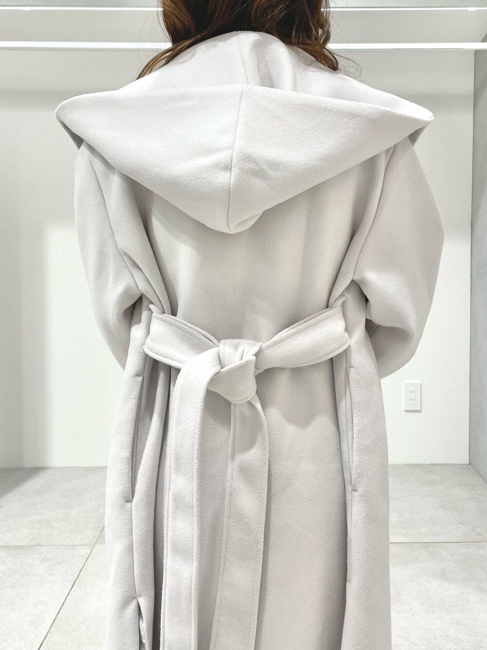 ホワイト系のチェスターコート、ピンク系のハンドバッグ、ホワイト系のワンピースを着用したレディースの冬コーディネートの5枚目の写真