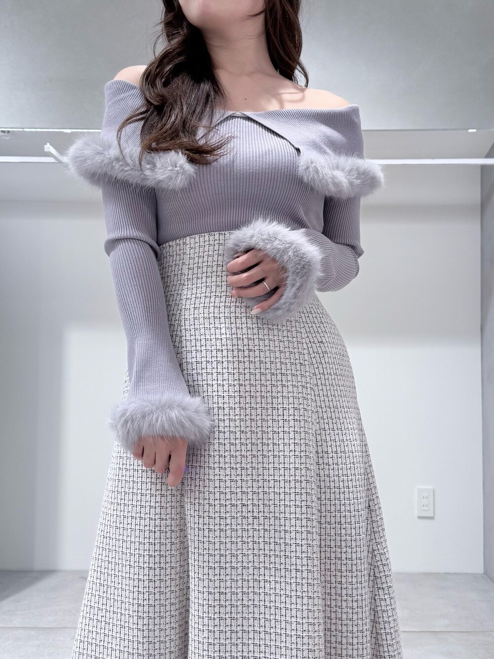 グレー系のニット/セーター、ホワイト系のスカート、ホワイト系のブーツを着用したレディースの冬コーディネートの6枚目の写真