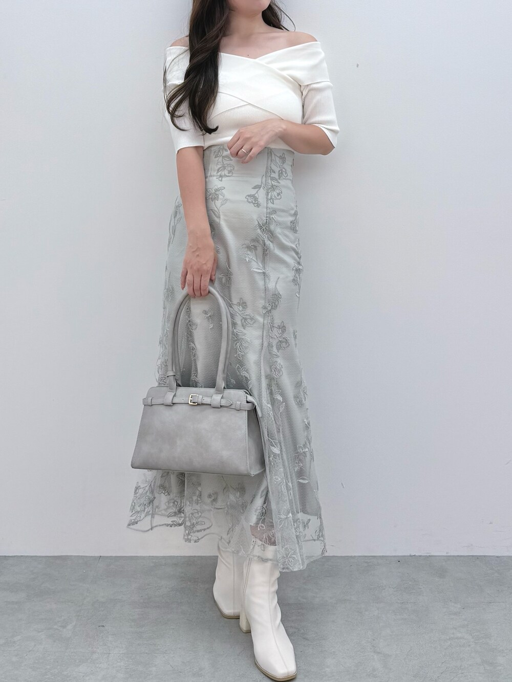 ホワイト系のニット/セーター、ホワイト系のブーツ、グリーン系のスカートを着用したレディースの秋コーディネートの2枚目の写真