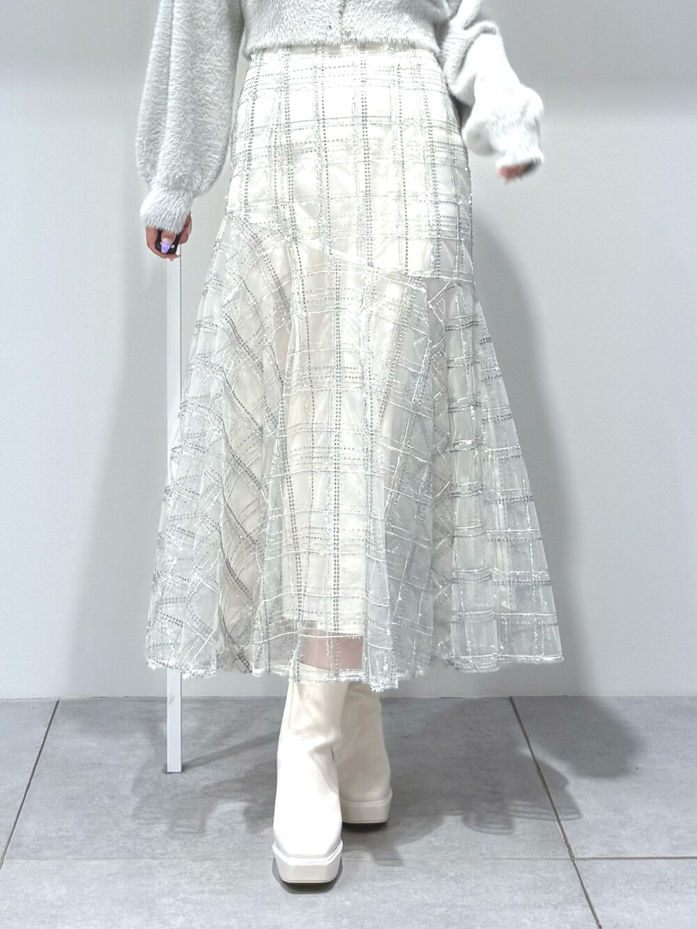 グレー系のカーディガン/ボレロ、ホワイト系のスカート、ホワイト系のブーツを着用したレディースの秋コーディネートの7枚目の写真