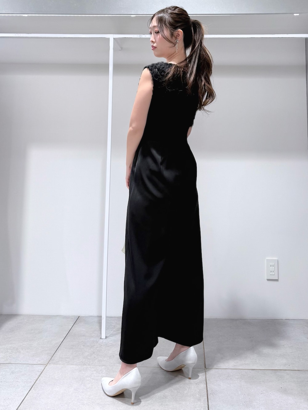 ブラック系のドレス、ゴールド系のショルダーバッグ、シルバー系のパンプスを着用したレディースの冬コーディネートの3枚目の写真