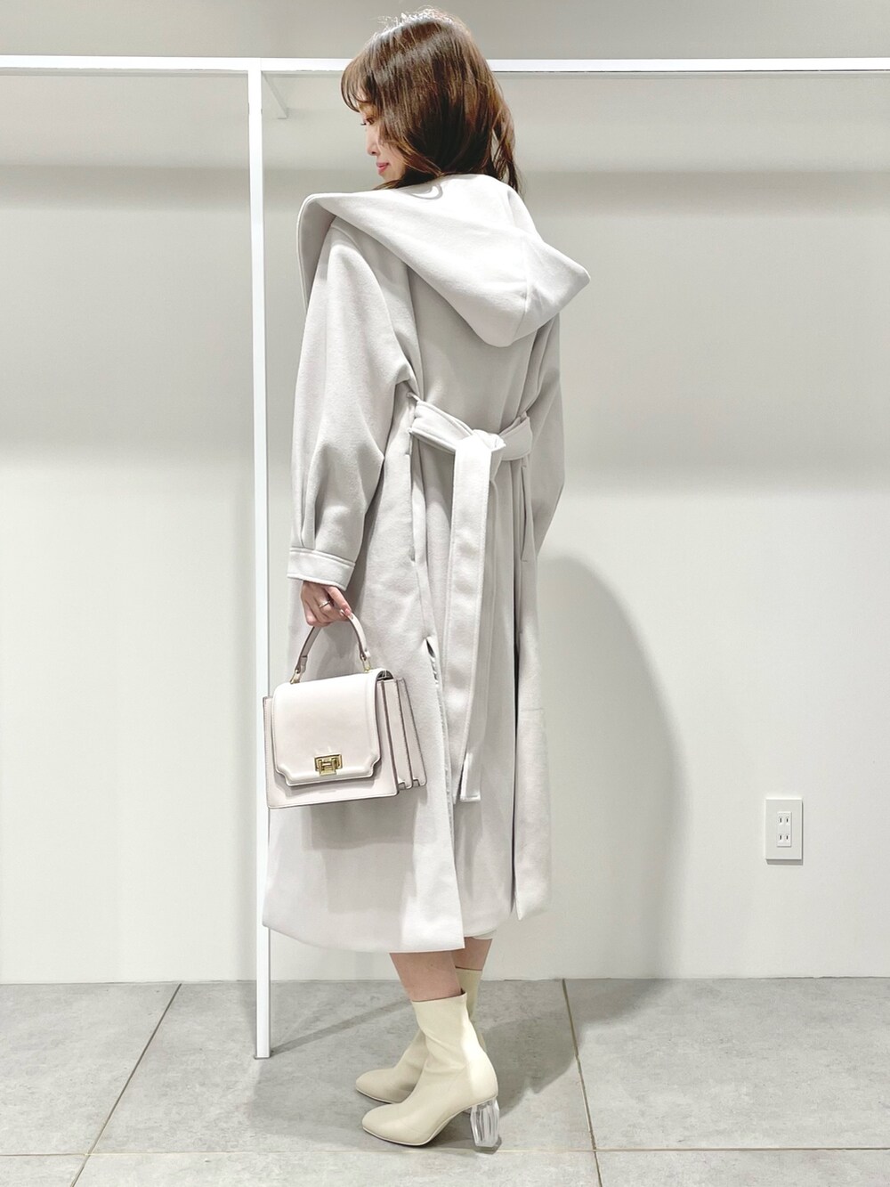 ホワイト系のチェスターコート、ピンク系のハンドバッグ、ホワイト系のワンピースを着用したレディースの冬コーディネートの2枚目の写真