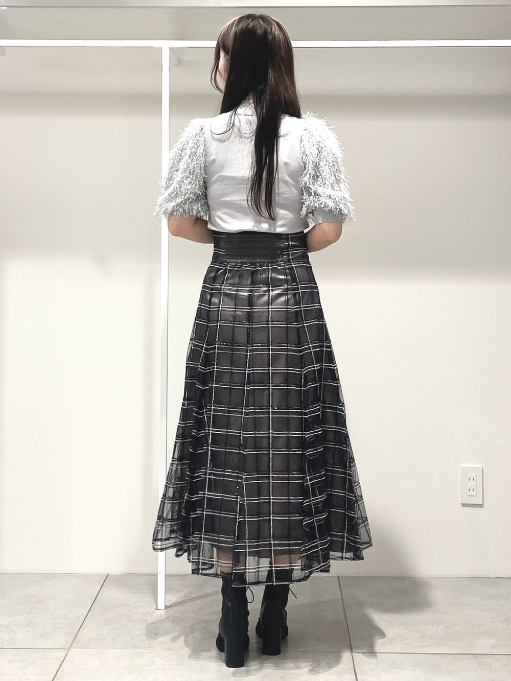 グレー系のニット/セーター、ブラック系のハンドバッグ、ブラック系のスカートを着用したレディースの秋コーディネートの4枚目の写真