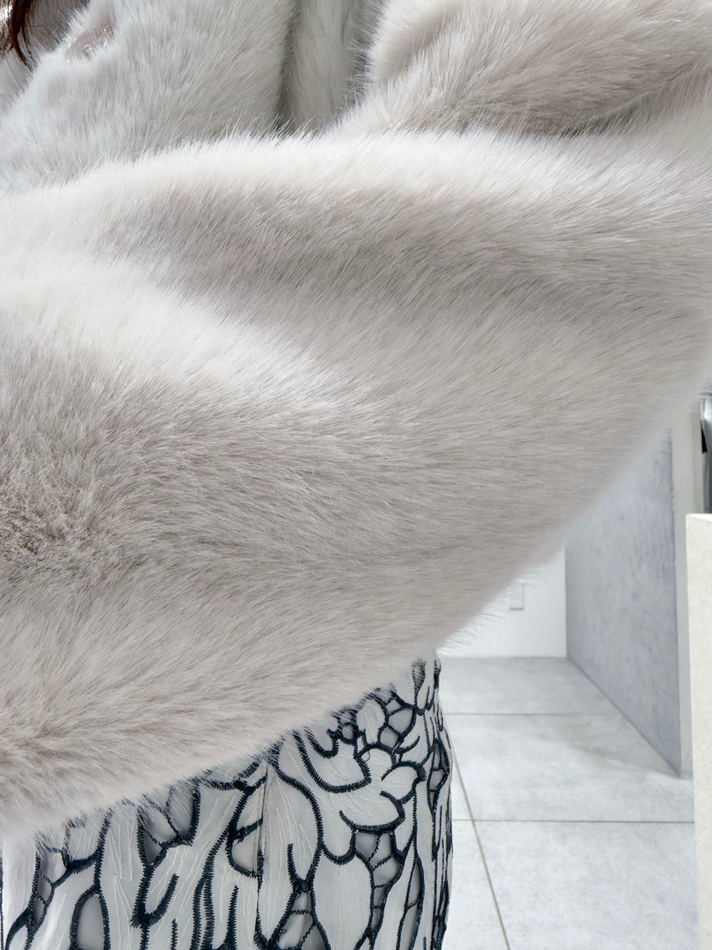 ホワイト系のその他アウター、ブラック系のブーツ、ホワイト系のハンドバッグを着用したレディースの冬コーディネートの7枚目の写真