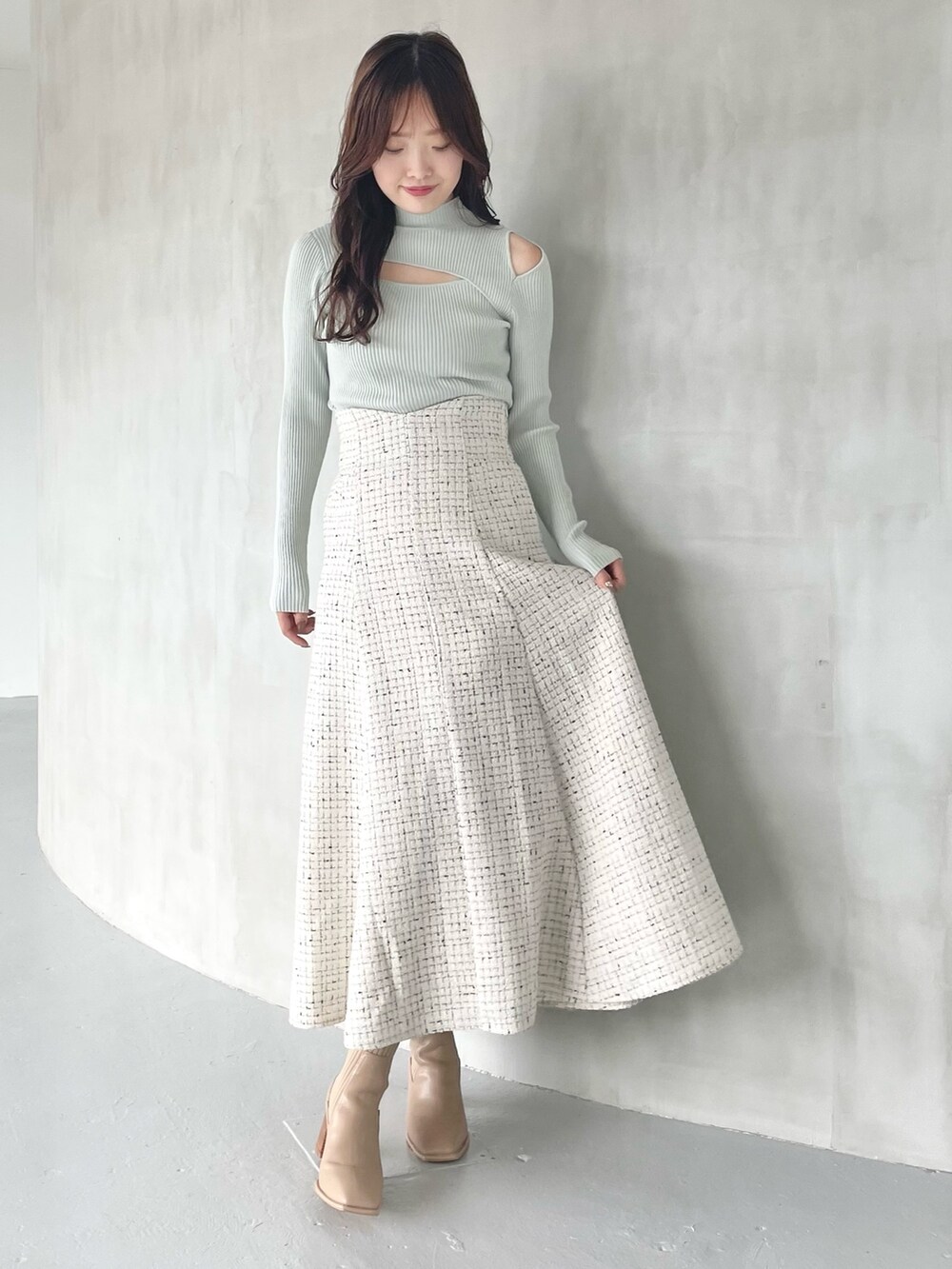 ホワイト系のスカート、ベージュ系のブーツ、グリーン系のニット/セーターを着用したレディースの秋コーディネートの4枚目の写真