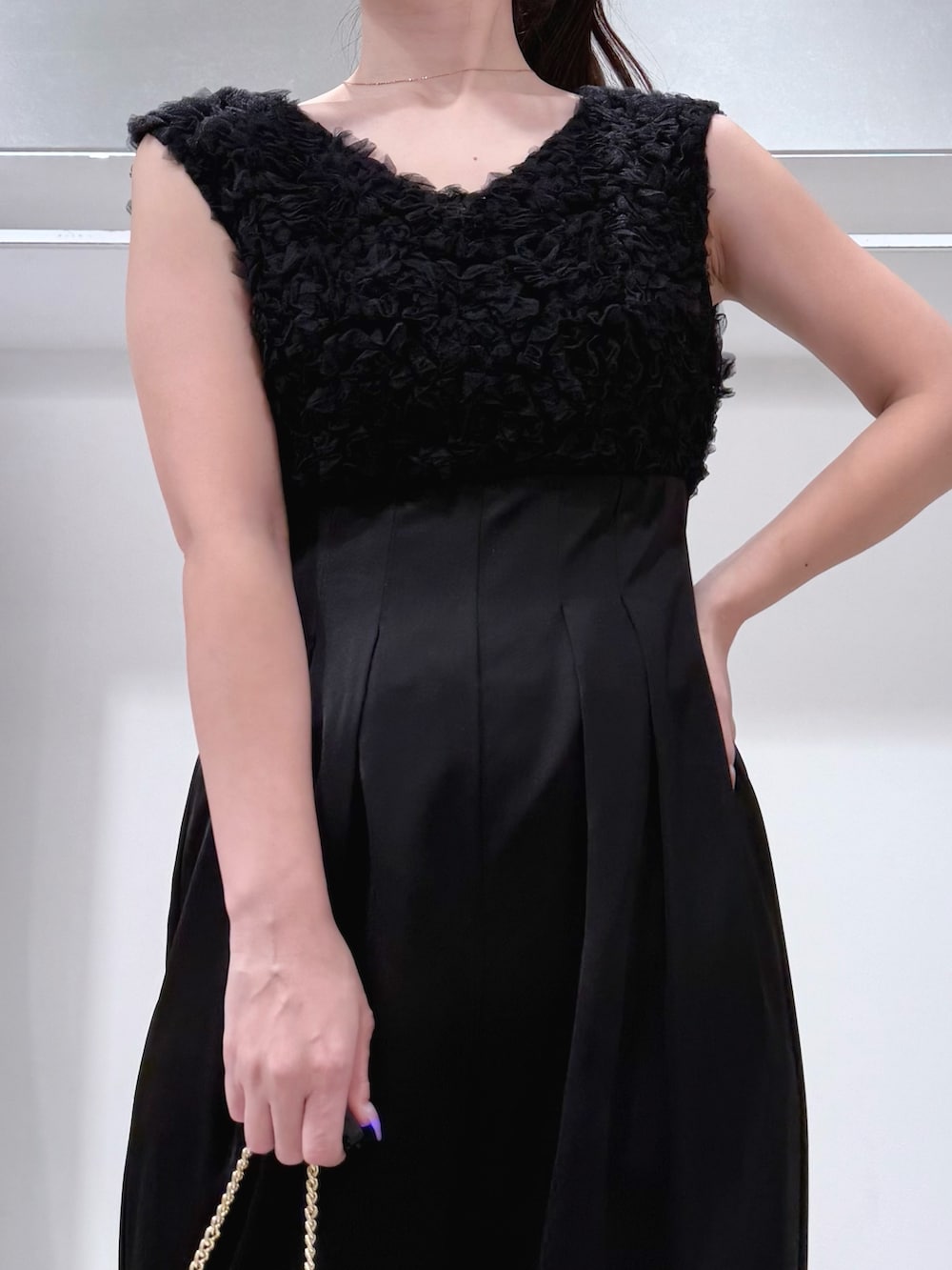 ブラック系のドレス、ゴールド系のショルダーバッグ、シルバー系のパンプスを着用したレディースの冬コーディネートの5枚目の写真