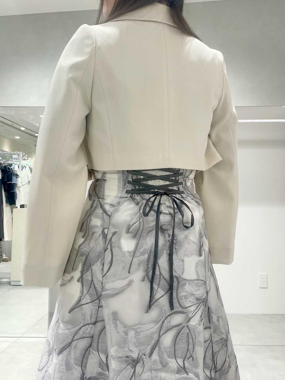 シルバー系のハンドバッグ、ホワイト系のテーラードジャケット、ブルー系のニット/セーターを着用したレディースの春コーディネートの5枚目の写真