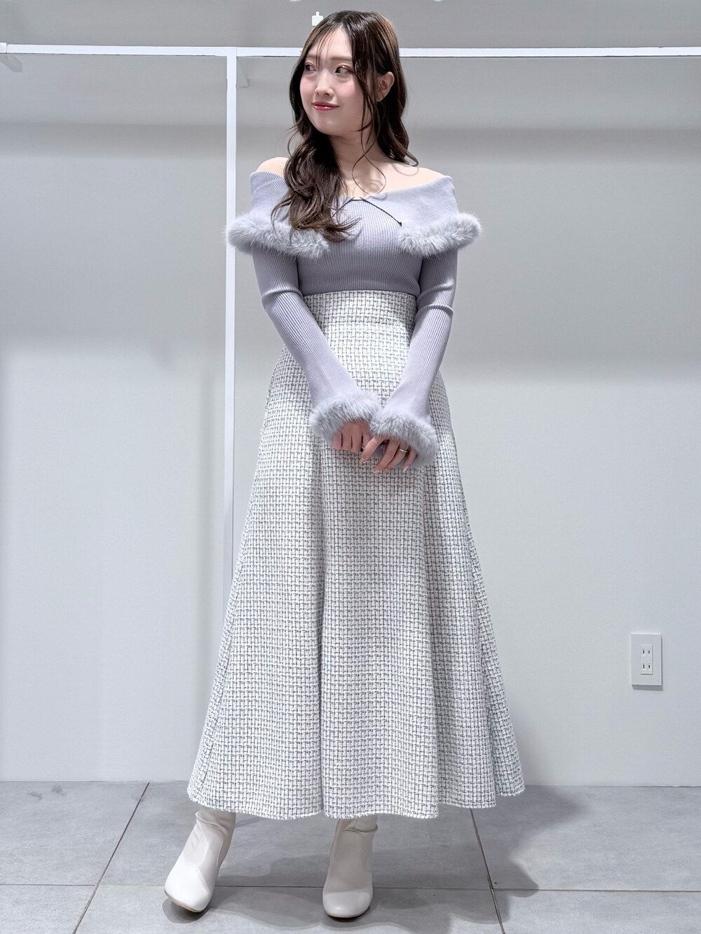 グレー系のニット/セーター、ホワイト系のスカート、ホワイト系のブーツを着用したレディースの冬コーディネートの2枚目の写真