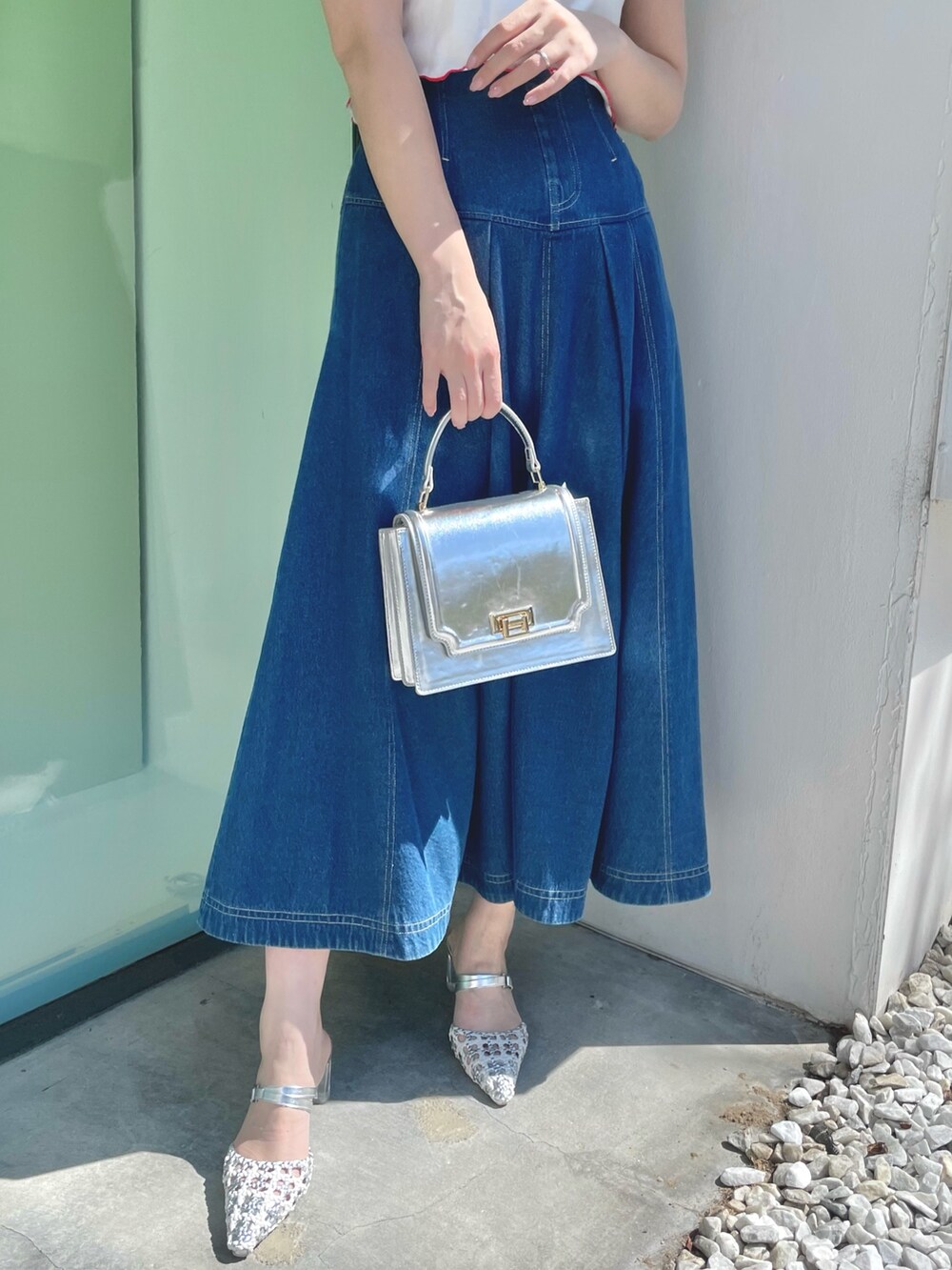 ブルー系のスカート、シルバー系のハンドバッグ、シルバー系のパンプスを着用したレディースの春コーディネートの8枚目の写真