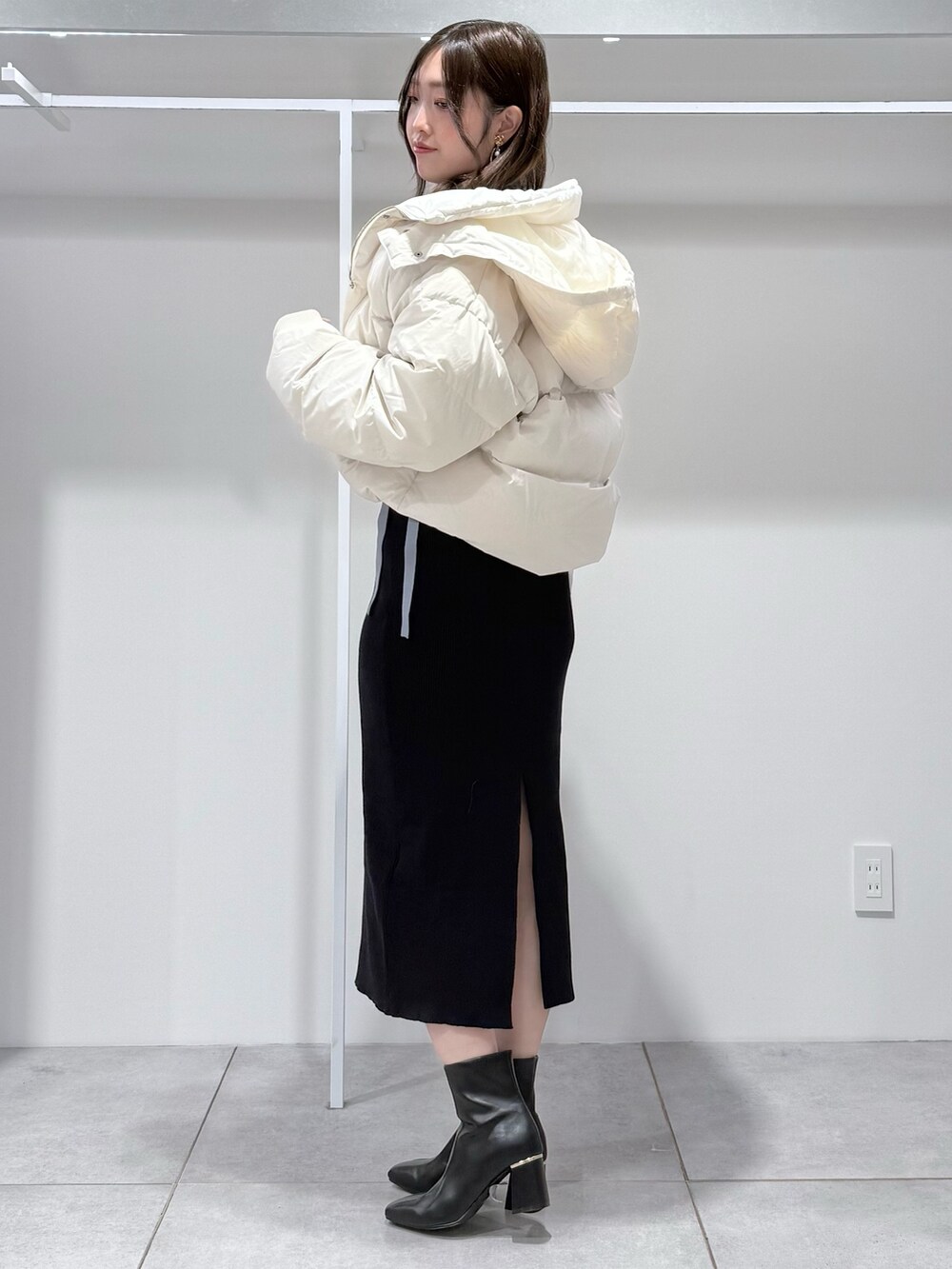 ホワイト系のダウンジャケット/コート、ブルー系のワンピース、ブラック系のブーツを着用したレディースの冬コーディネートの2枚目の写真