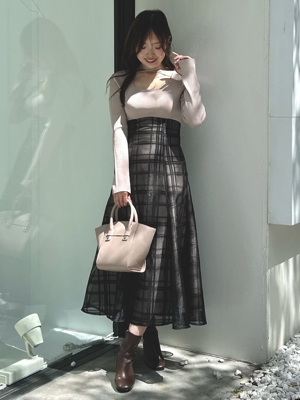 ピンク系のワンピース、ベージュ系のハンドバッグ、ホワイト系のライダースジャケットを着用したレディースの秋コーディネートの4枚目の写真