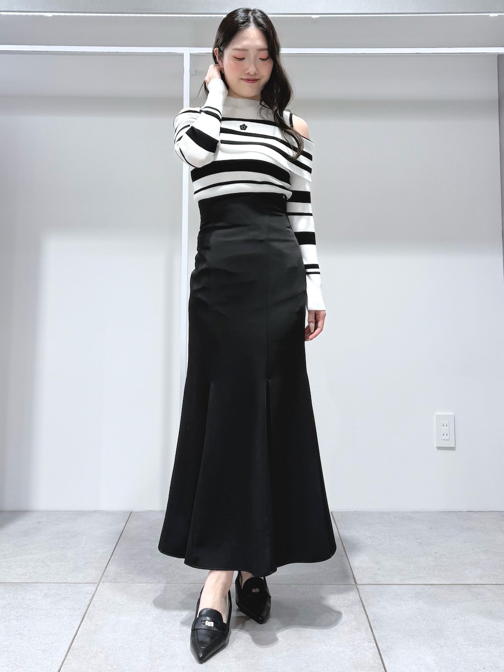 その他のニット/セーター、ブラック系のスカート、ブラック系のパンプスを着用したレディースの春コーディネートの2枚目の写真