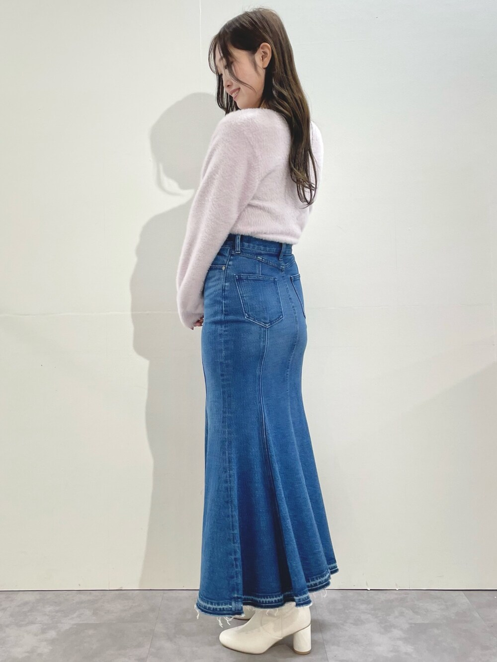 ピンク系のカーディガン/ボレロ、ブルー系のスカート、ホワイト系のブーツを着用したレディースの冬コーディネートの2枚目の写真