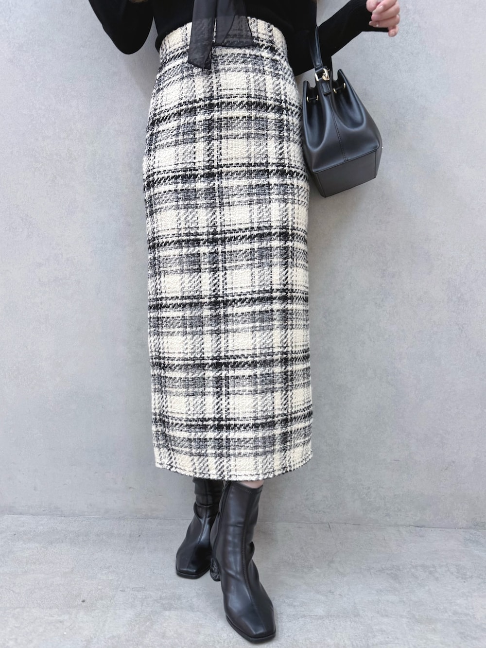 ブラック系のニット/セーター、ホワイト系のスカート、ブラック系のブーツを着用したレディースの冬コーディネートの6枚目の写真