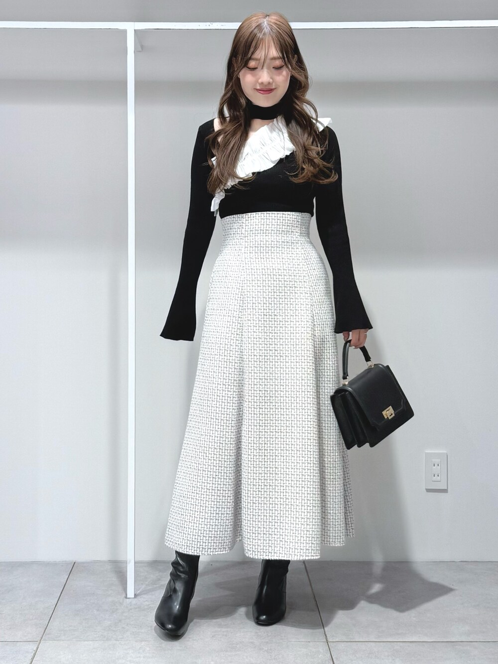 ブラック系のニット/セーター、ブラック系のハンドバッグ、ブラック系のブーツを着用したレディースの秋コーディネートの2枚目の写真