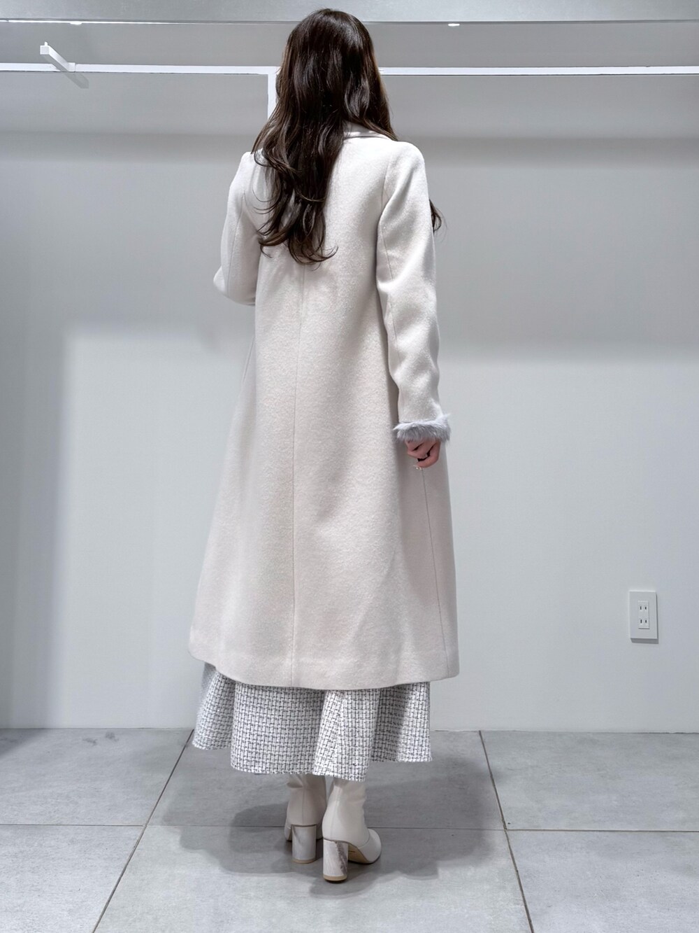 ホワイト系のチェスターコート、ホワイト系のスカート、グレー系のニット/セーターを着用したレディースの冬コーディネートの3枚目の写真