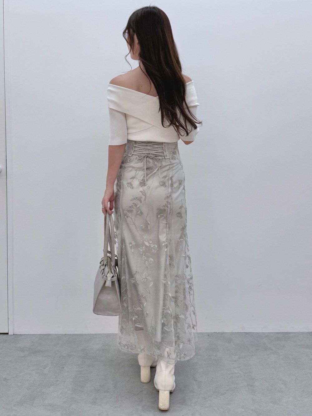 ホワイト系のニット/セーター、ホワイト系のブーツ、グリーン系のスカートを着用したレディースの秋コーディネートの4枚目の写真