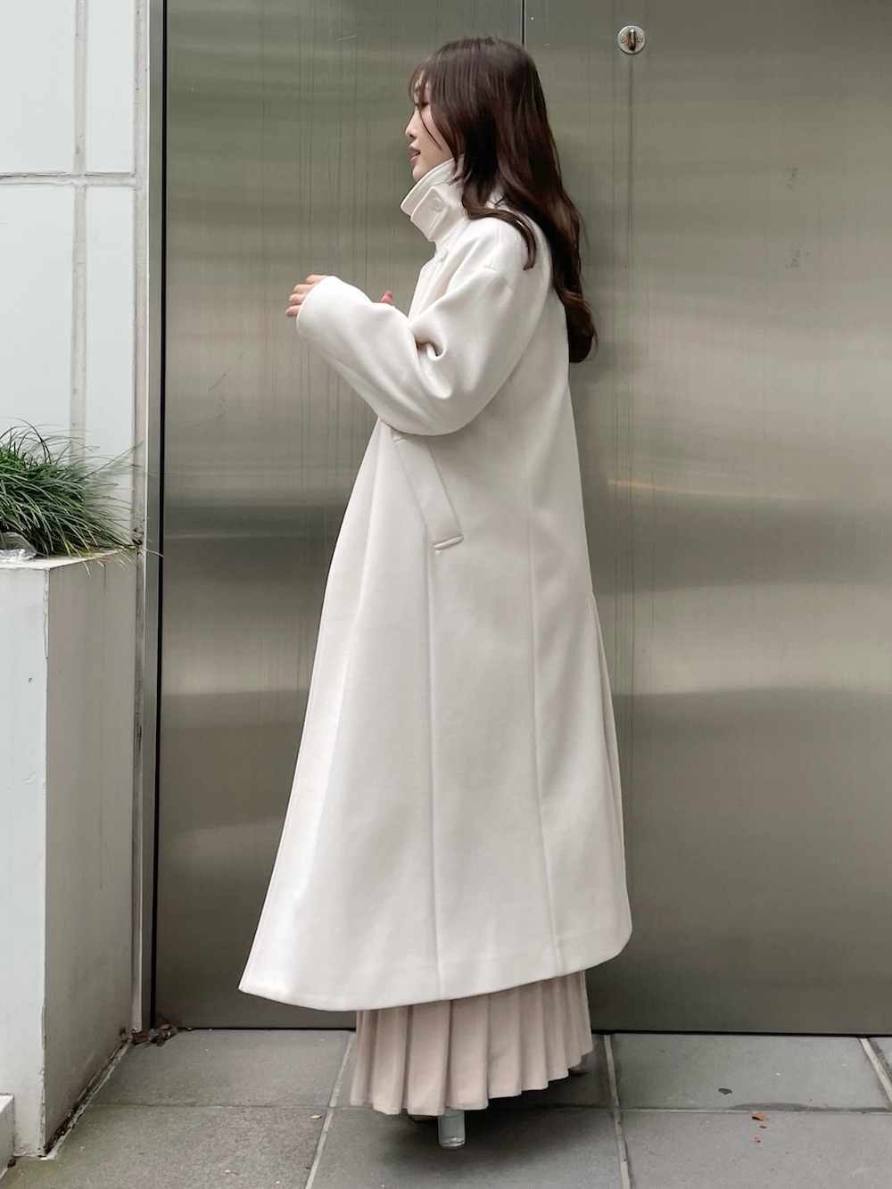 ホワイト系のステンカラーコート、ベージュ系のワンピース、ベージュ系のブーツを着用したレディースの秋コーディネートの4枚目の写真