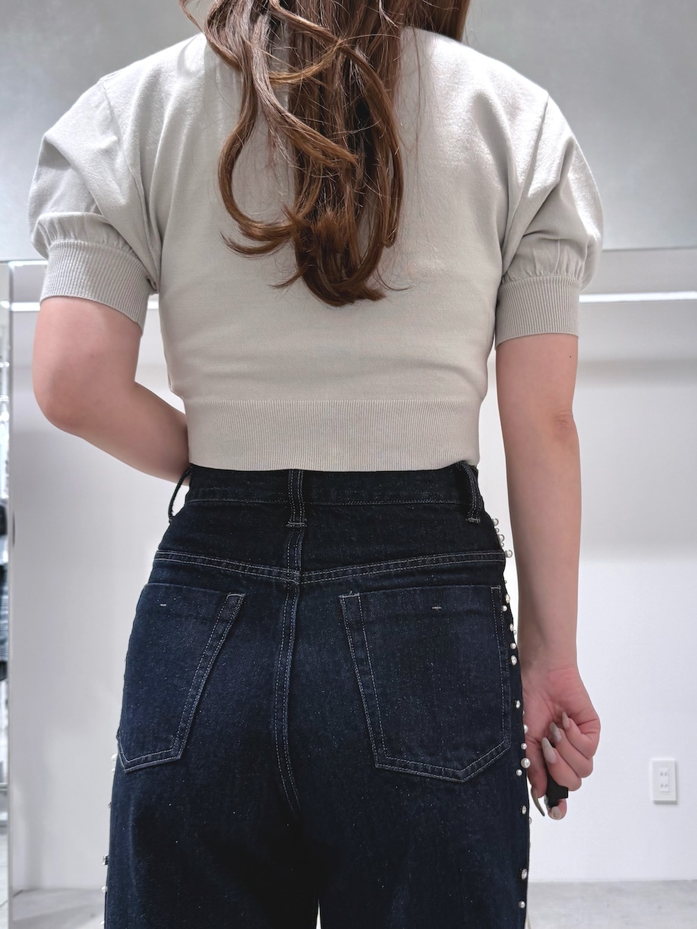 グリーン系のニット/セーター、ブルー系のデニムパンツ、ブラウン系のハンドバッグを着用したレディースの夏コーディネートの6枚目の写真