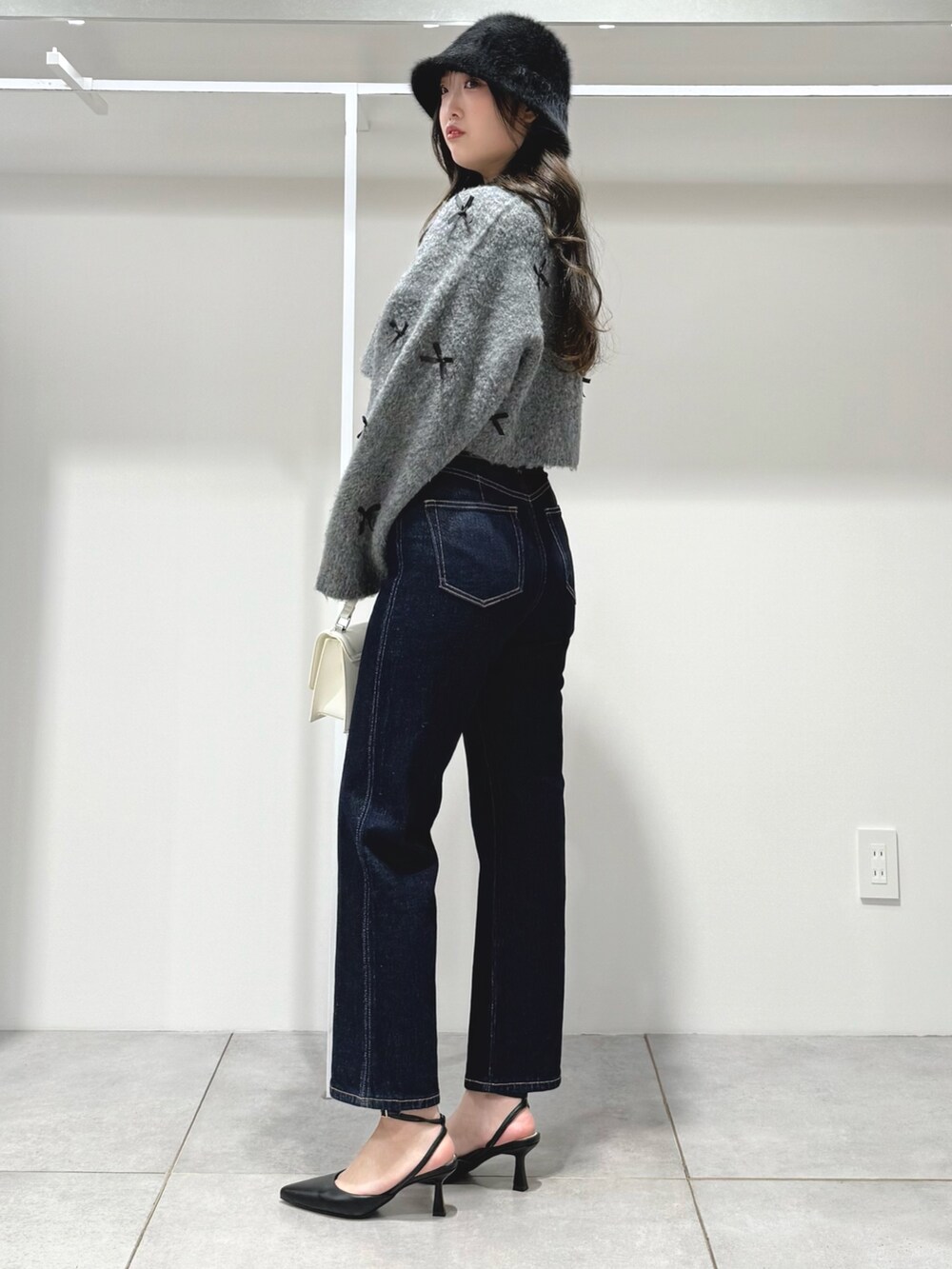 グレー系のカーディガン/ボレロ、ブルー系のデニムパンツ、ホワイト系のショルダーバッグを着用したレディースの冬コーディネートの3枚目の写真