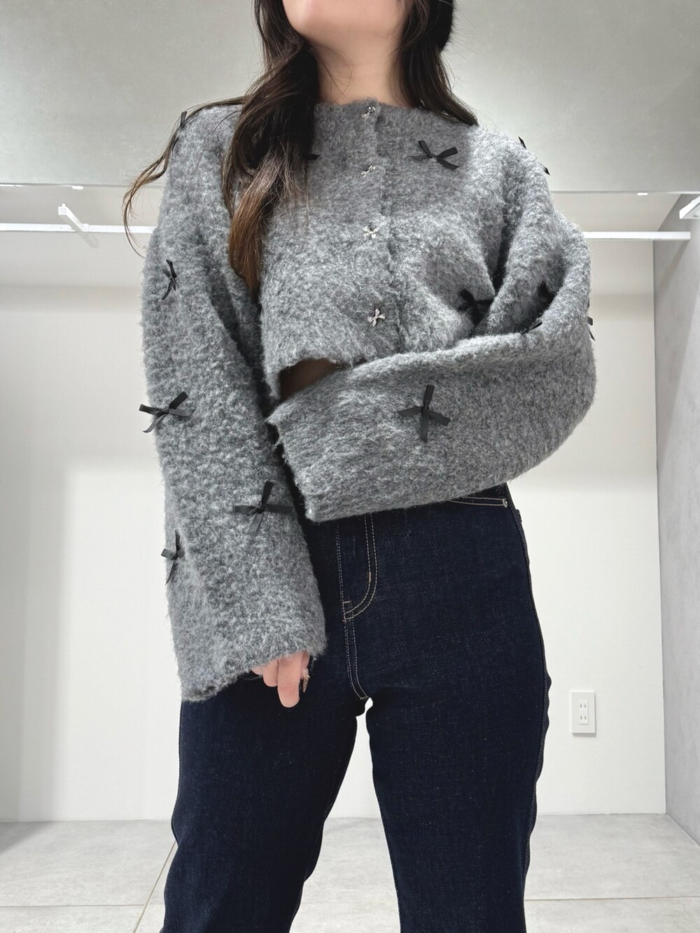 グレー系のカーディガン/ボレロ、ブルー系のデニムパンツ、ホワイト系のショルダーバッグを着用したレディースの冬コーディネートの5枚目の写真