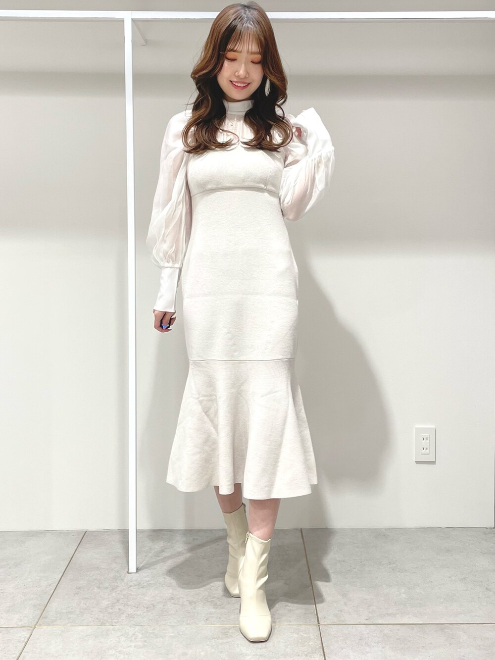 ホワイト系のチェスターコート、ピンク系のハンドバッグ、ホワイト系のワンピースを着用したレディースの冬コーディネートの6枚目の写真