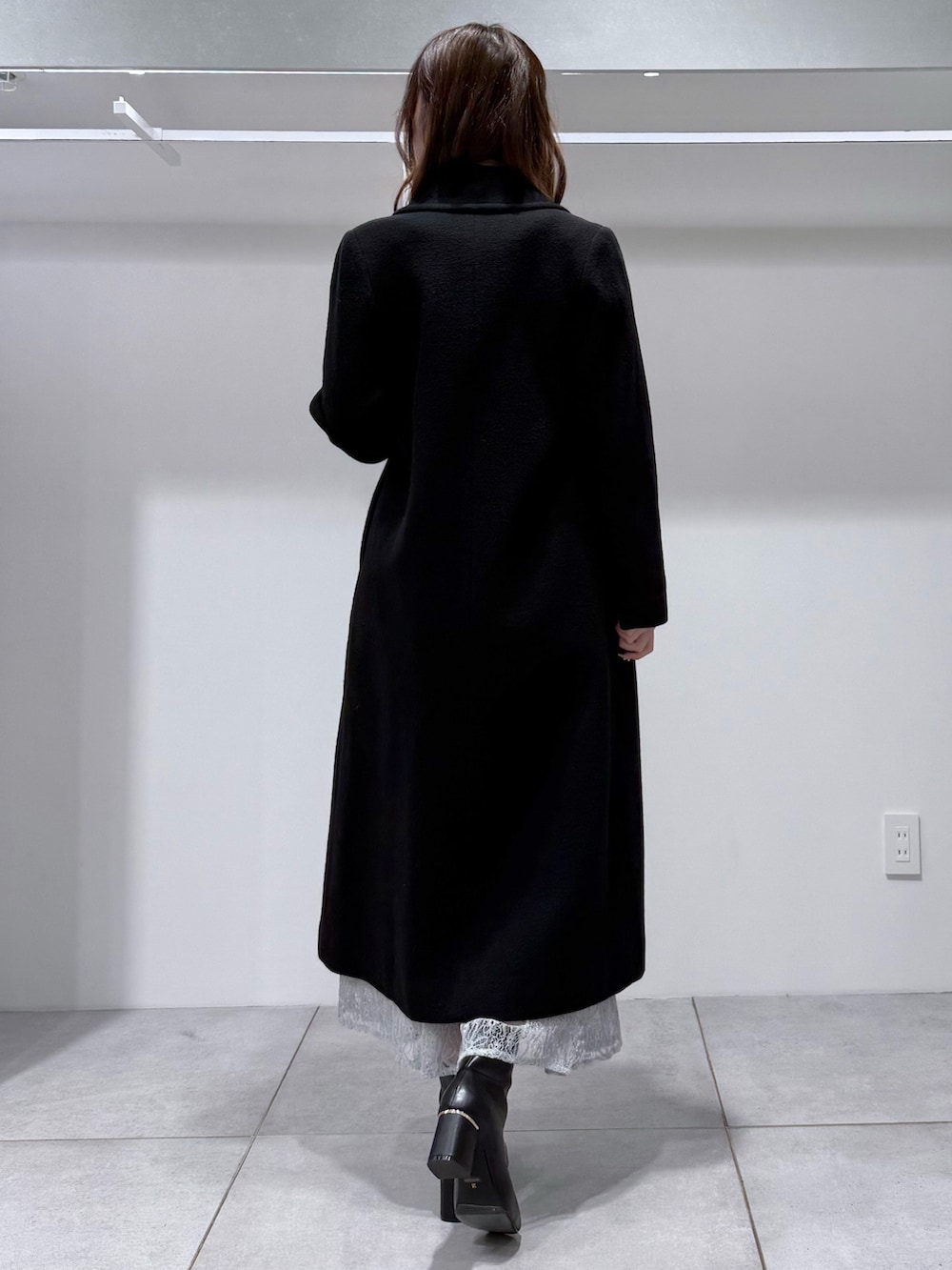 ブラック系のチェスターコート、ブラック系のニット/セーター、ブルー系のスカートを着用したレディースの冬コーディネートの4枚目の写真