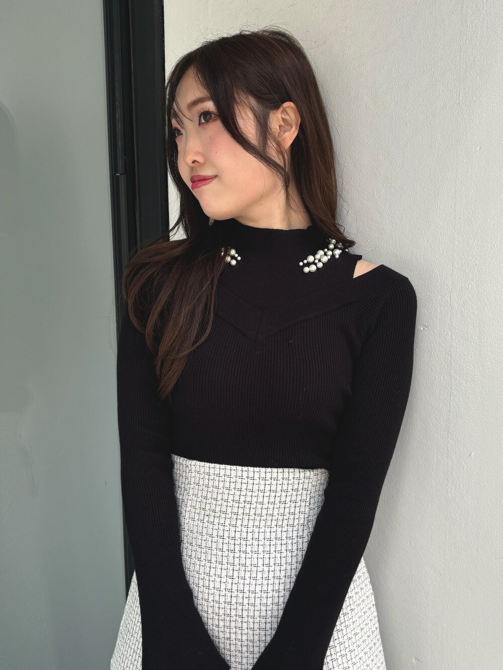 ブラック系のニット/セーター、レッド系のハンドバッグ、ホワイト系のスカートを着用したレディースの冬コーディネートの5枚目の写真