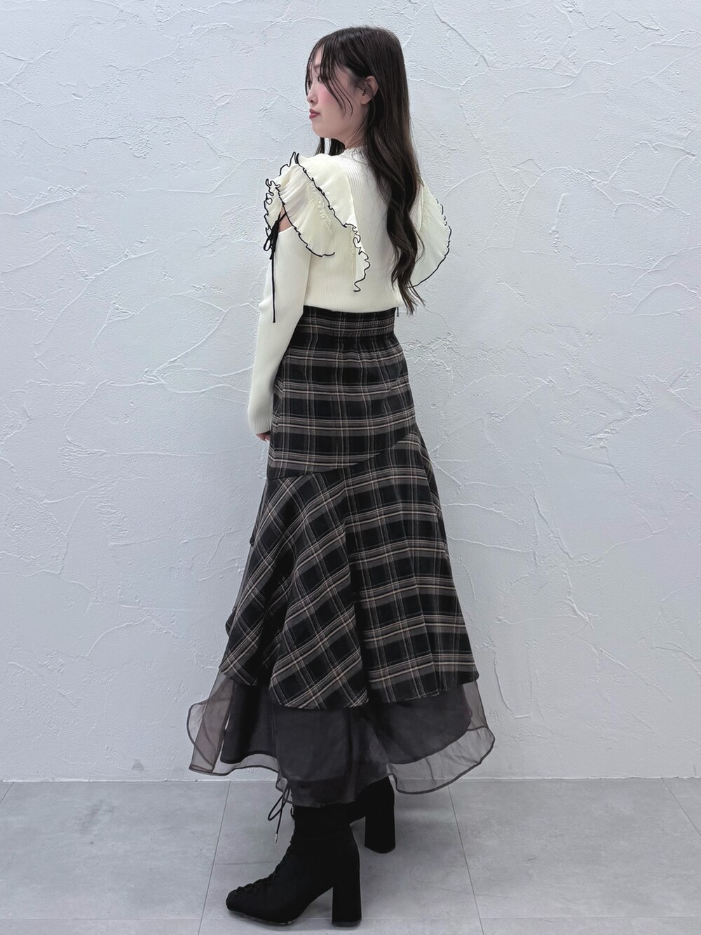 グレー系のスカート、ブラック系のブーツ、ホワイト系のニット/セーターを着用したレディースの秋コーディネートの2枚目の写真