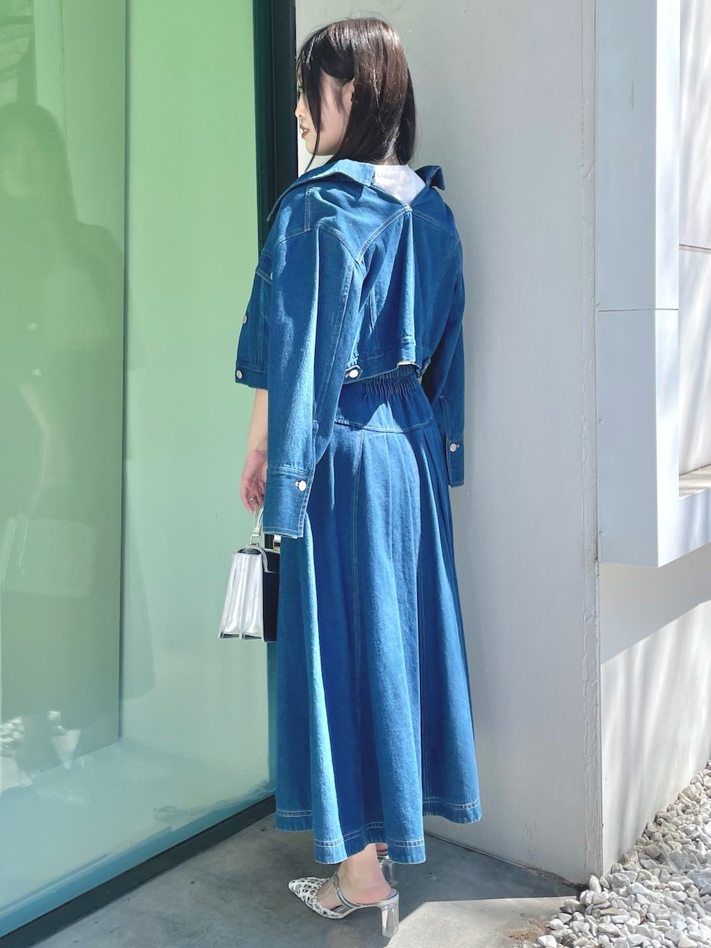 ブルー系のスカート、シルバー系のハンドバッグ、シルバー系のパンプスを着用したレディースの春コーディネートの2枚目の写真