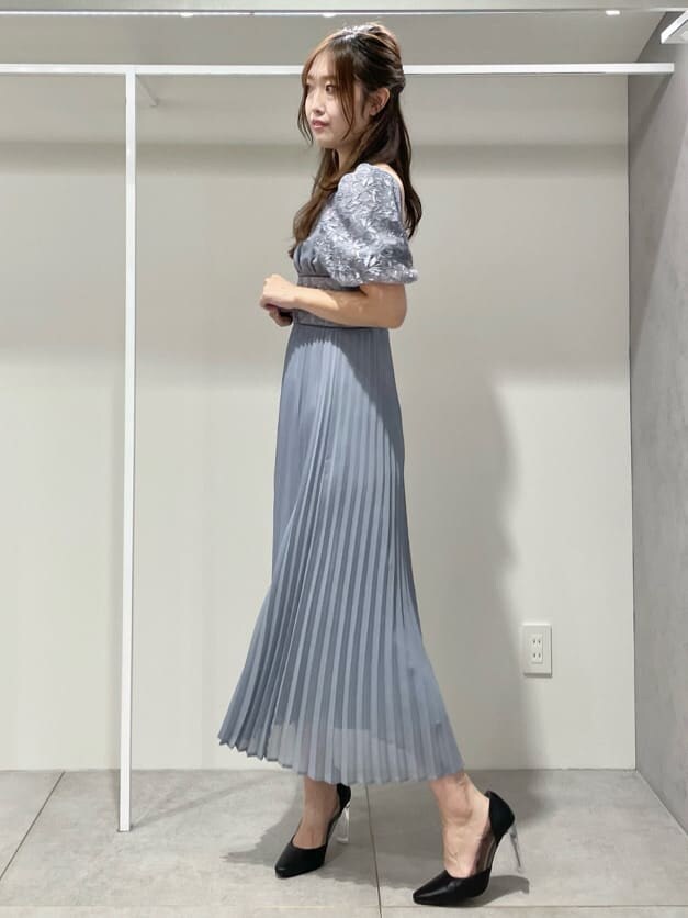 ブラック系のパンプス、ブルー系のワンピース、シルバー系のイヤリングを着用したレディースの秋コーディネートの2枚目の写真