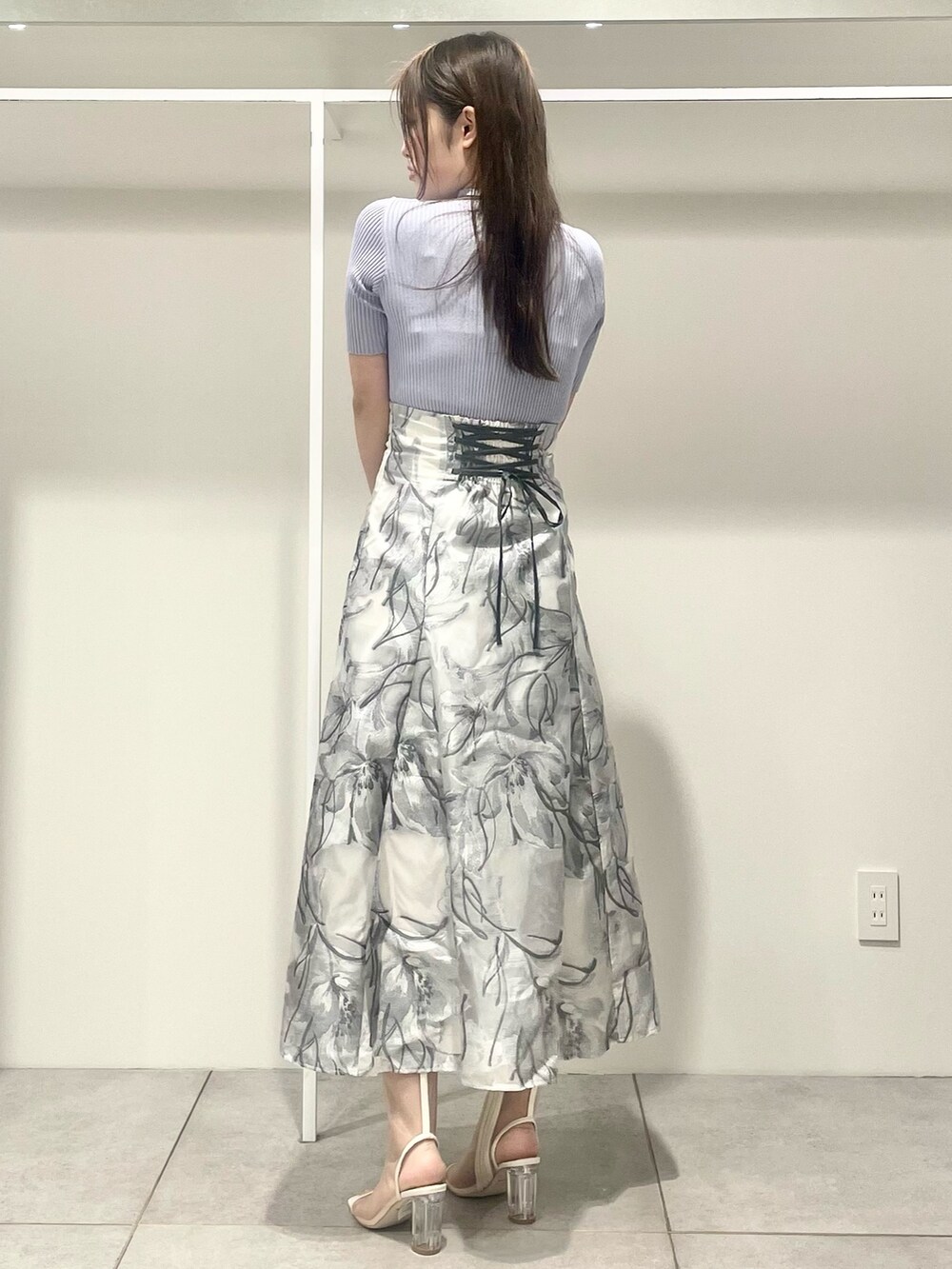 シルバー系のハンドバッグ、ホワイト系のテーラードジャケット、ブルー系のニット/セーターを着用したレディースの春コーディネートの7枚目の写真