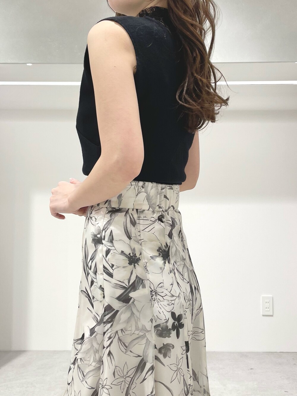 ブラック系のニット/セーター、ホワイト系のスカート、ブラック系のサンダルを着用したレディースの春コーディネートの6枚目の写真