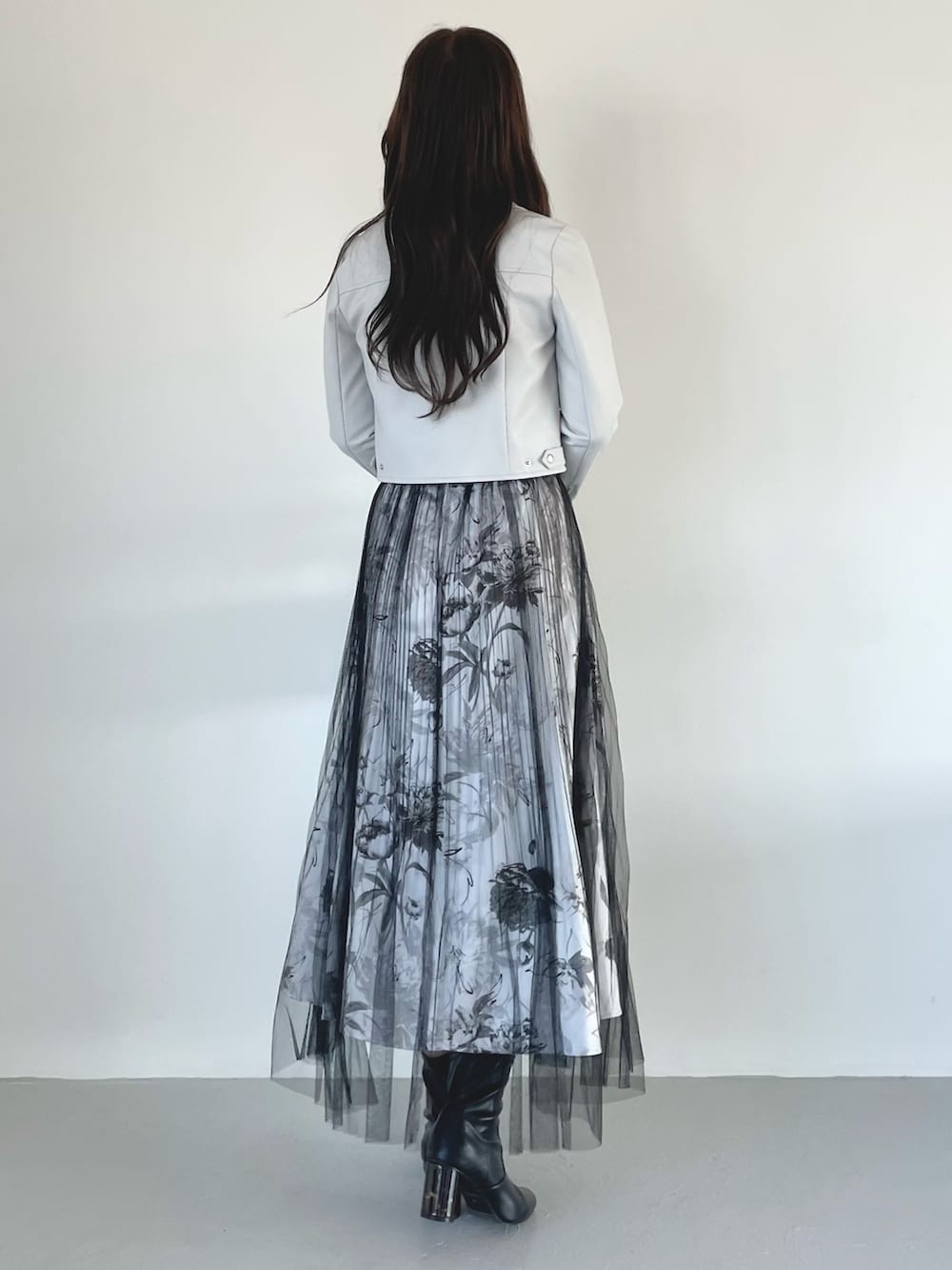 ブラック系のブーツ、ブラック系のスカート、ブラック系のハンドバッグを着用したレディースの春コーディネートの3枚目の写真