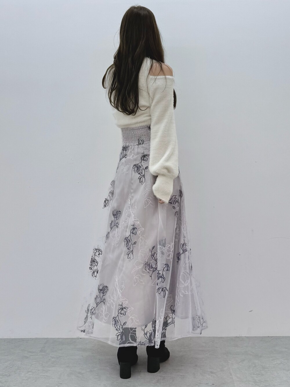 パープル系のスカート、ホワイト系のニット/セーター、ブラック系のブーツを着用したレディースの秋コーディネートの4枚目の写真