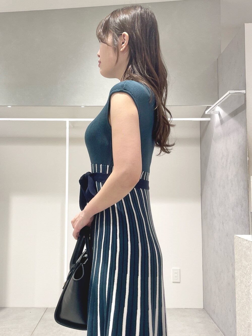 ブラック系のトートバッグ、ブラック系のサンダル、グリーン系のワンピースを着用したレディースの夏コーディネートの6枚目の写真