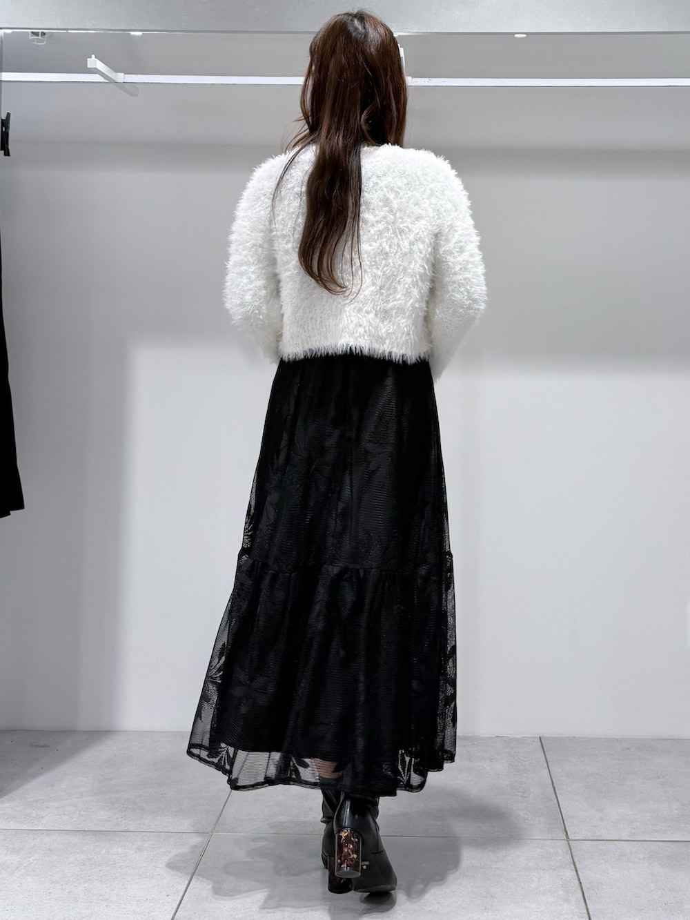 ブラック系のワンピース、ホワイト系のカーディガン/ボレロ、ホワイト系のハンドバッグを着用したレディースの冬コーディネートの5枚目の写真