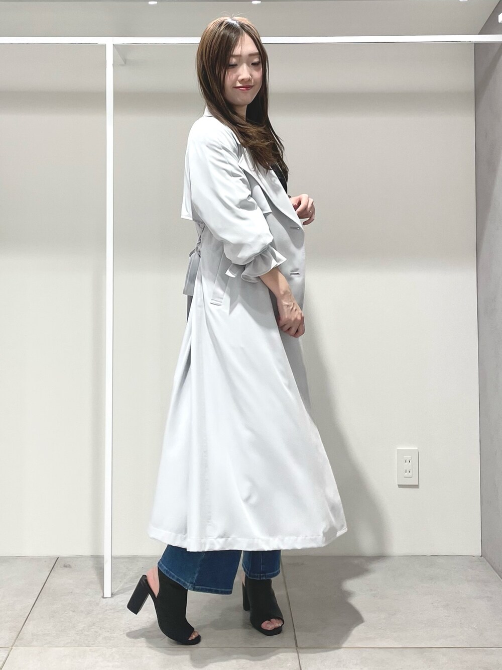 ブルー系のトレンチコート、ブルー系のデニムパンツ、ブラック系のブーツを着用したレディースの春コーディネートの2枚目の写真