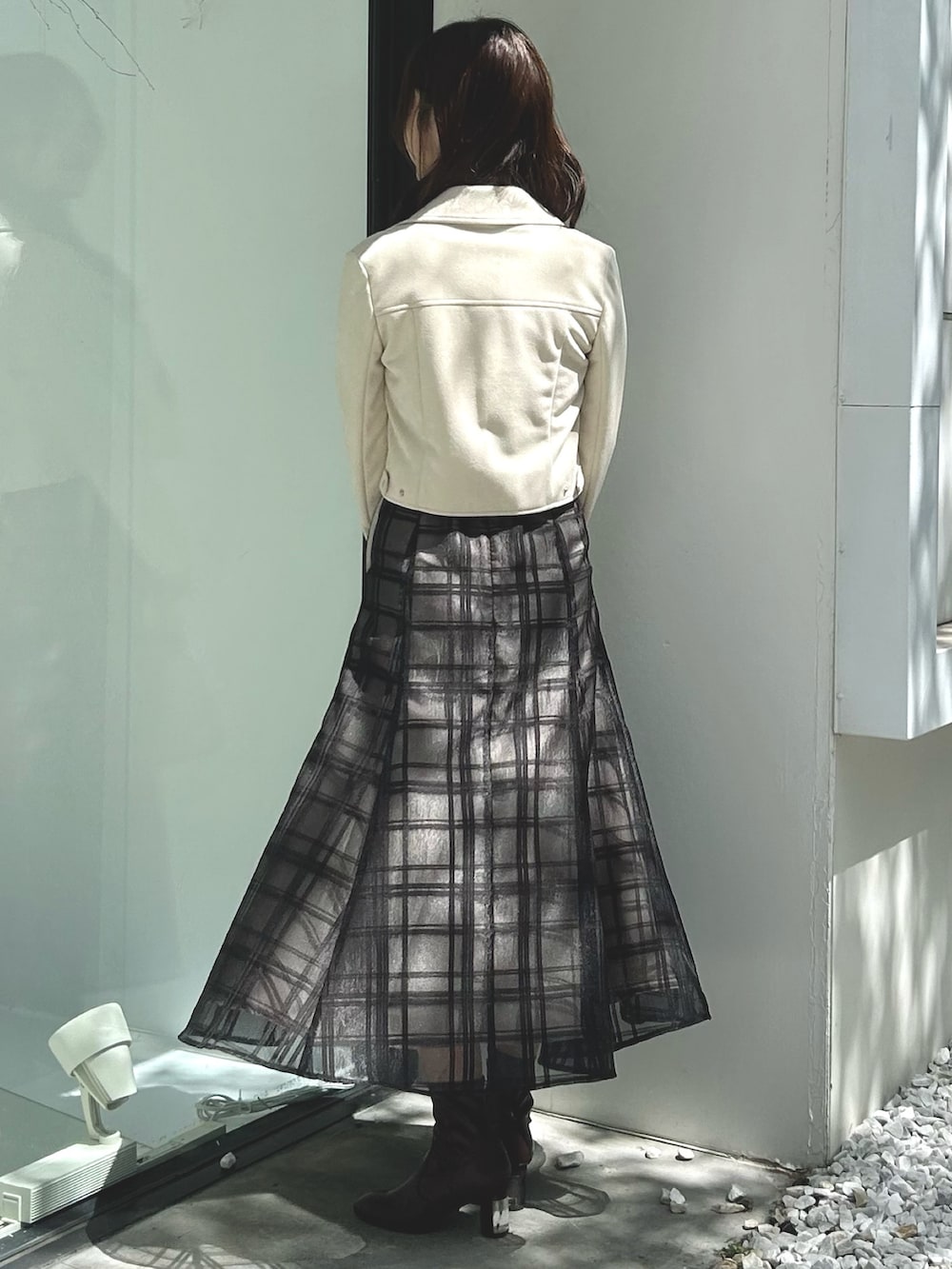 ピンク系のワンピース、ベージュ系のハンドバッグ、ホワイト系のライダースジャケットを着用したレディースの秋コーディネートの3枚目の写真