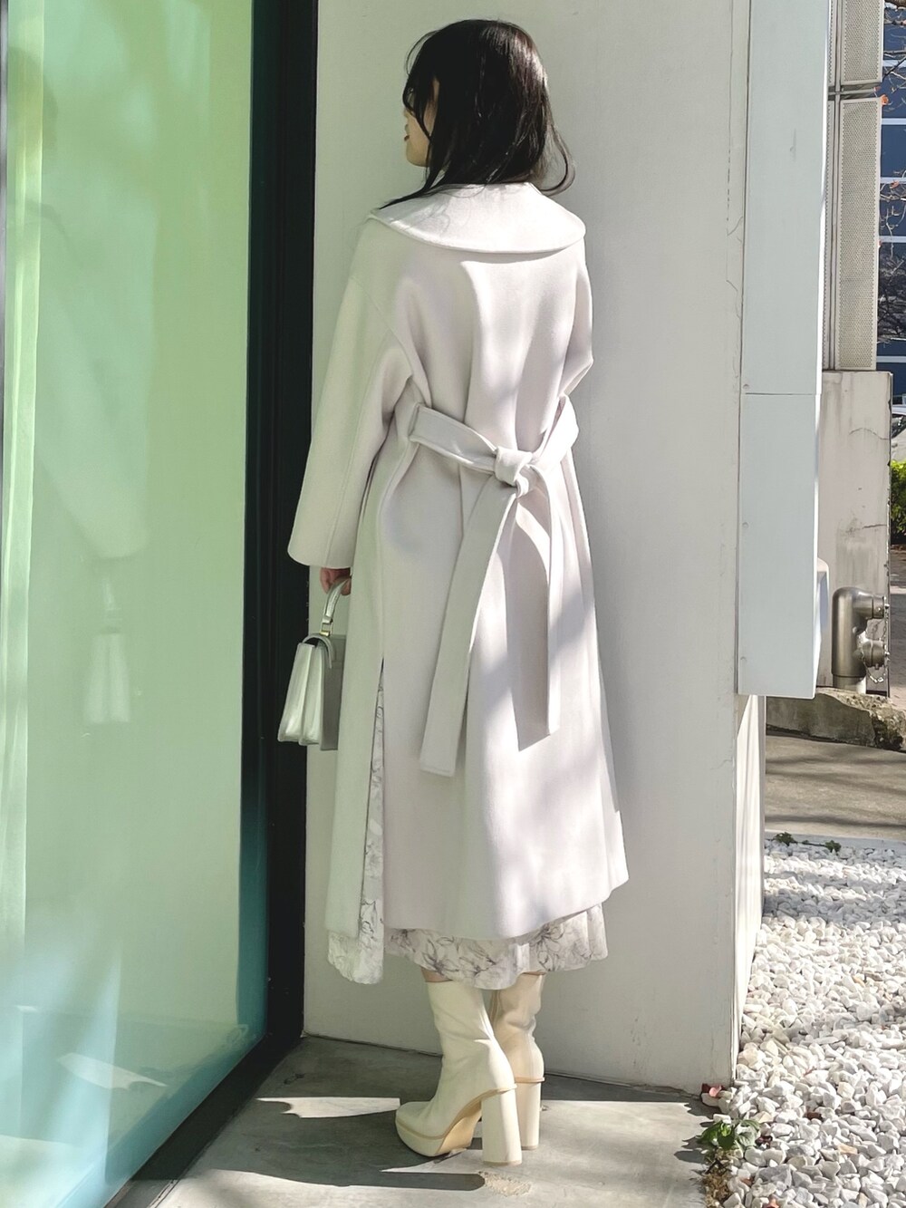 シルバー系のハンドバッグ、ホワイト系のブーツ、ホワイト系のチェスターコートを着用したレディースの冬コーディネートの2枚目の写真