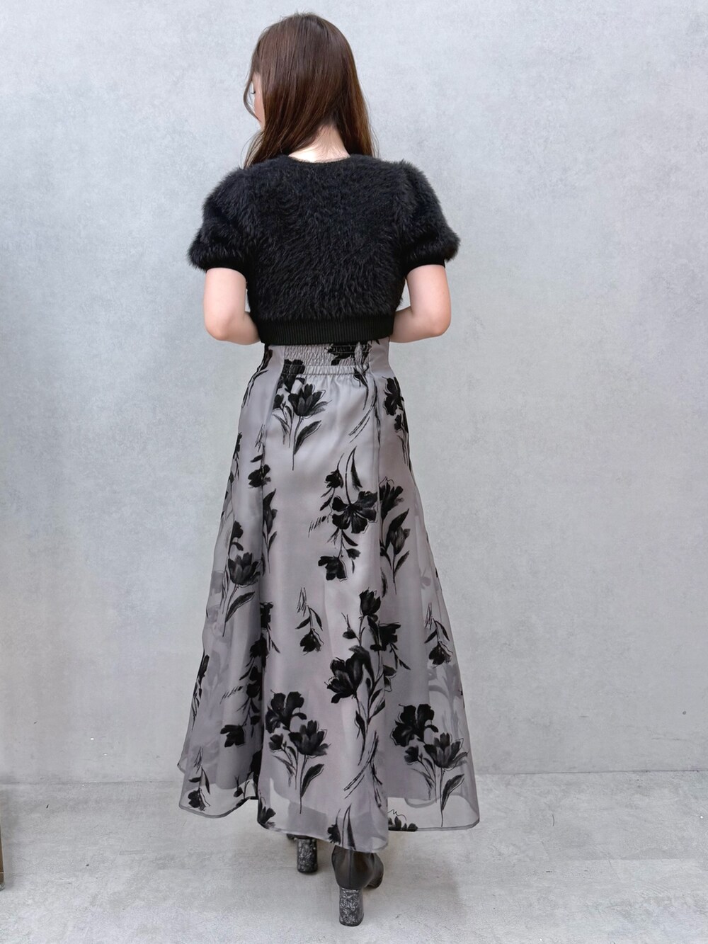 ブラック系のスカート、ブラック系のニット/セーター、ブラック系のブーツを着用したレディースの夏コーディネートの3枚目の写真