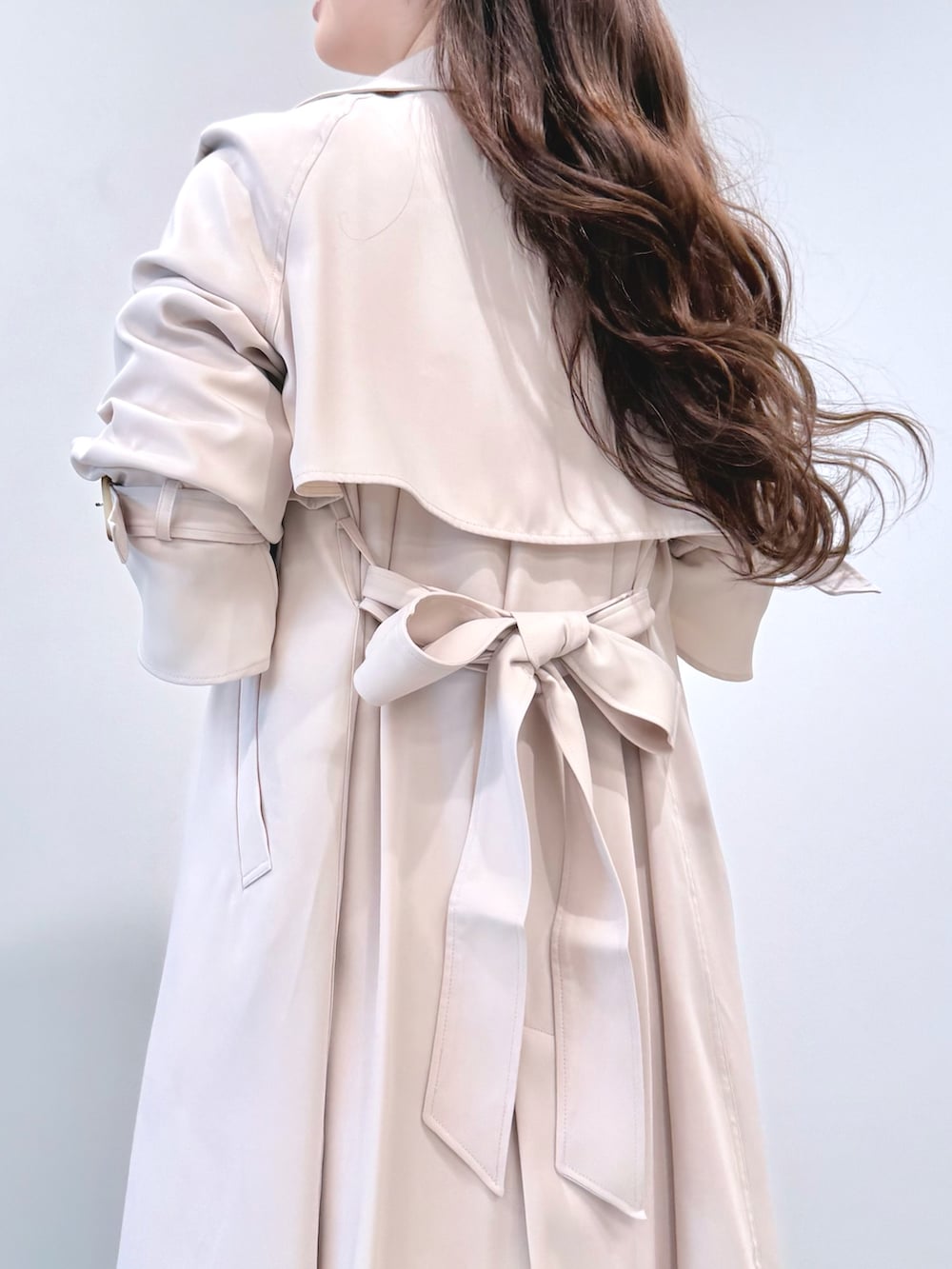 ベージュ系のワンピース、ホワイト系のパンプス、ホワイト系のトレンチコートを着用したレディースの冬コーディネートの7枚目の写真