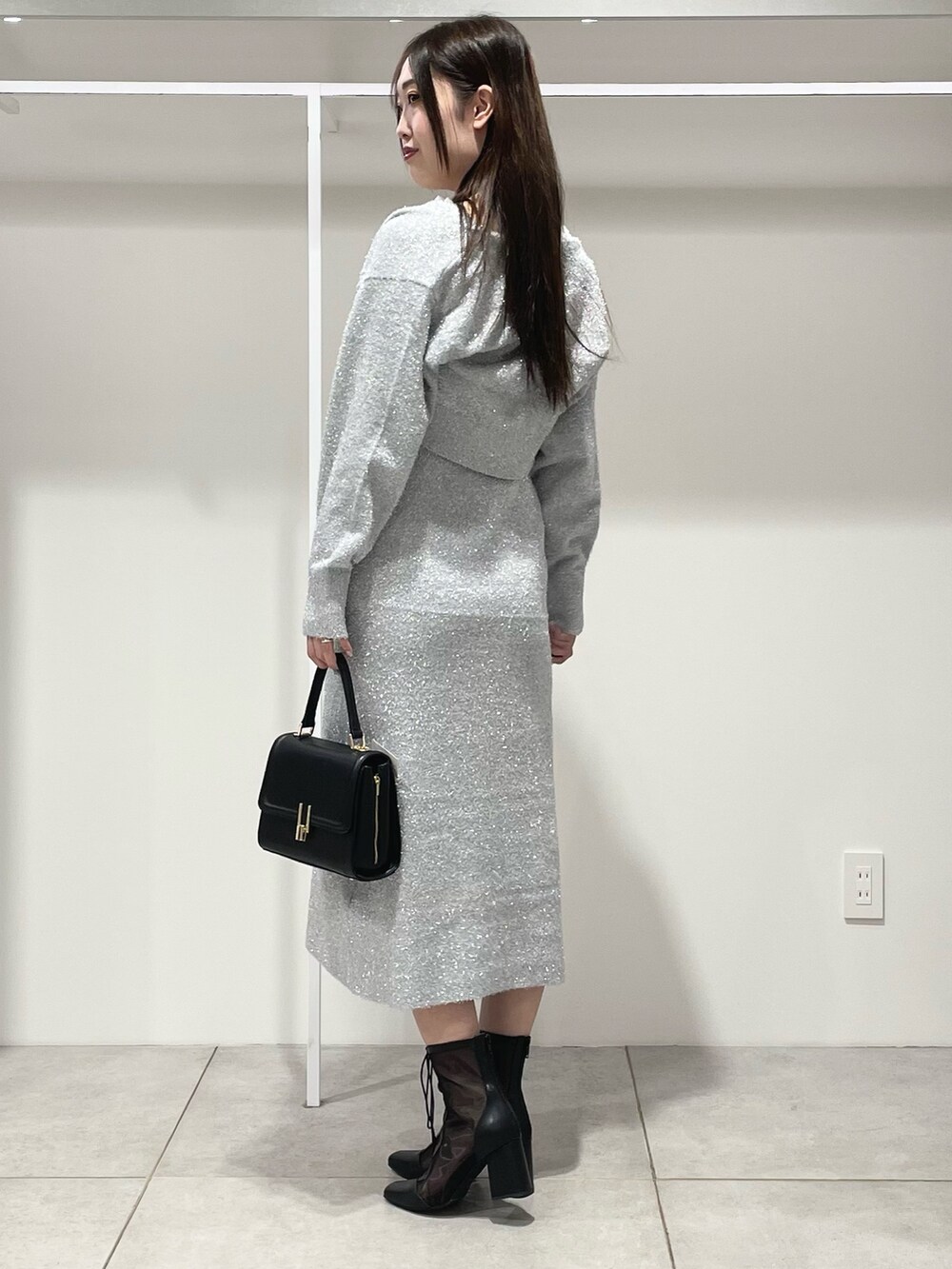 シルバー系のワンピース、ブラック系のショルダーバッグ、ブラック系のブーツを着用したレディースの秋コーディネートの3枚目の写真