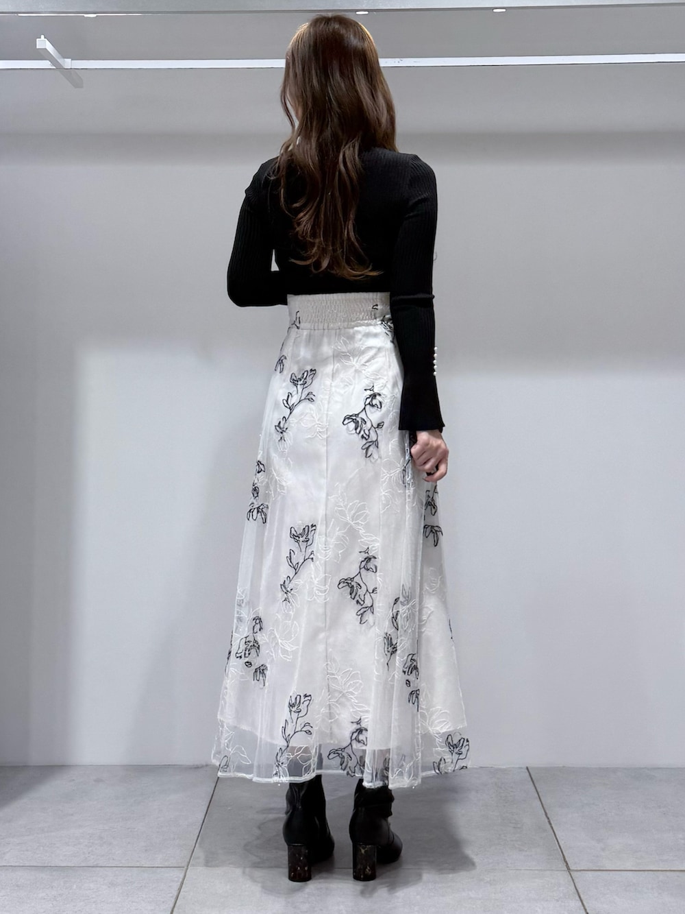 ブラック系のニット/セーター、ホワイト系のスカート、ブラック系のブーツを着用したレディースの冬コーディネートの4枚目の写真