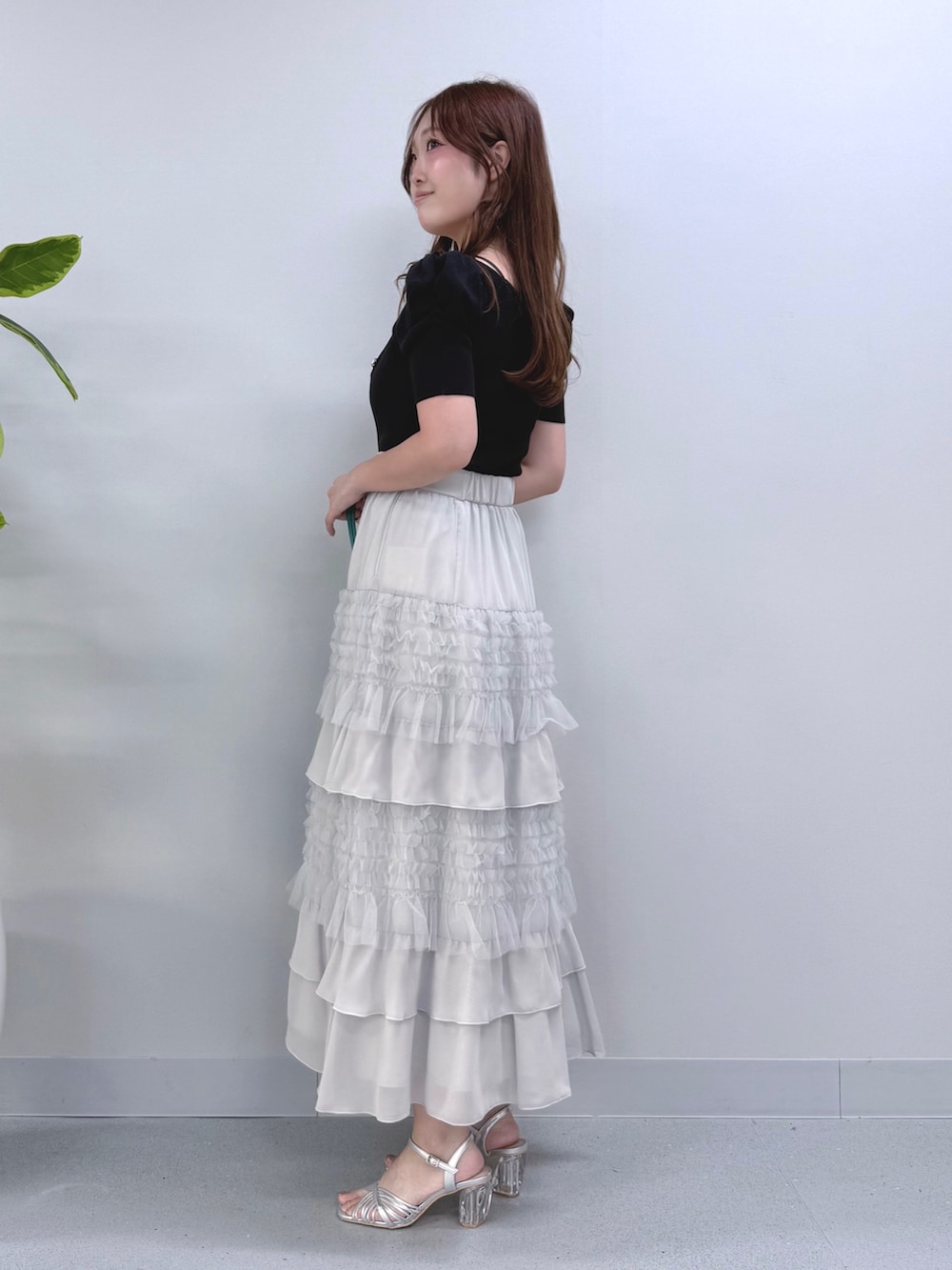 ブルー系のニット/セーター、グレー系のスカート、グリーン系のショルダーバッグを着用したレディースの夏コーディネートの2枚目の写真