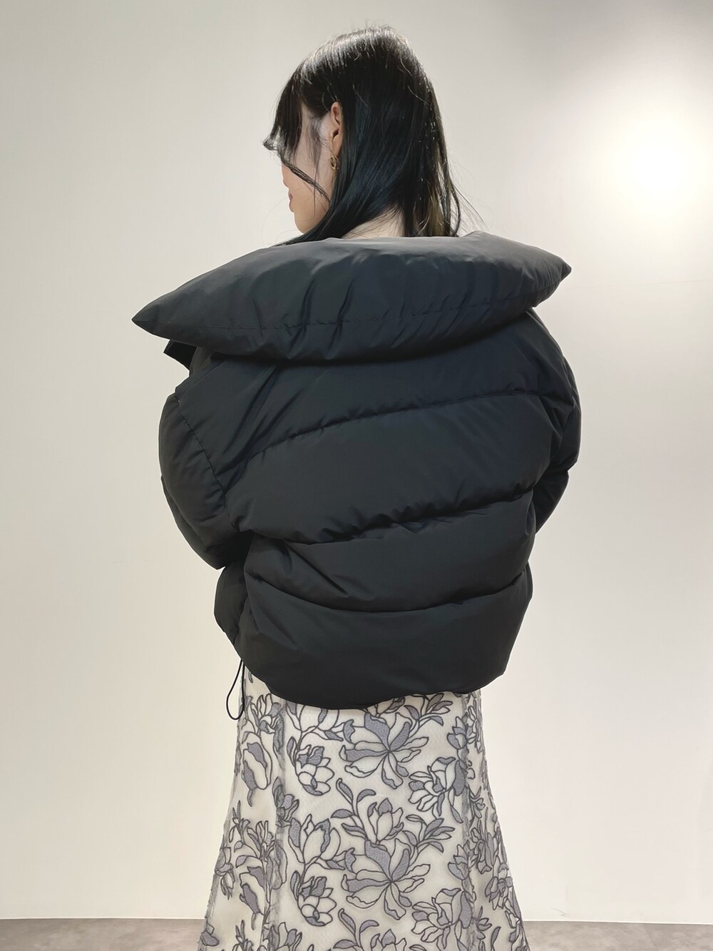 グレー系のスカート、ブラウン系のブーツ、ブラック系のダウンジャケット/コートを着用したレディースの冬コーディネートの6枚目の写真