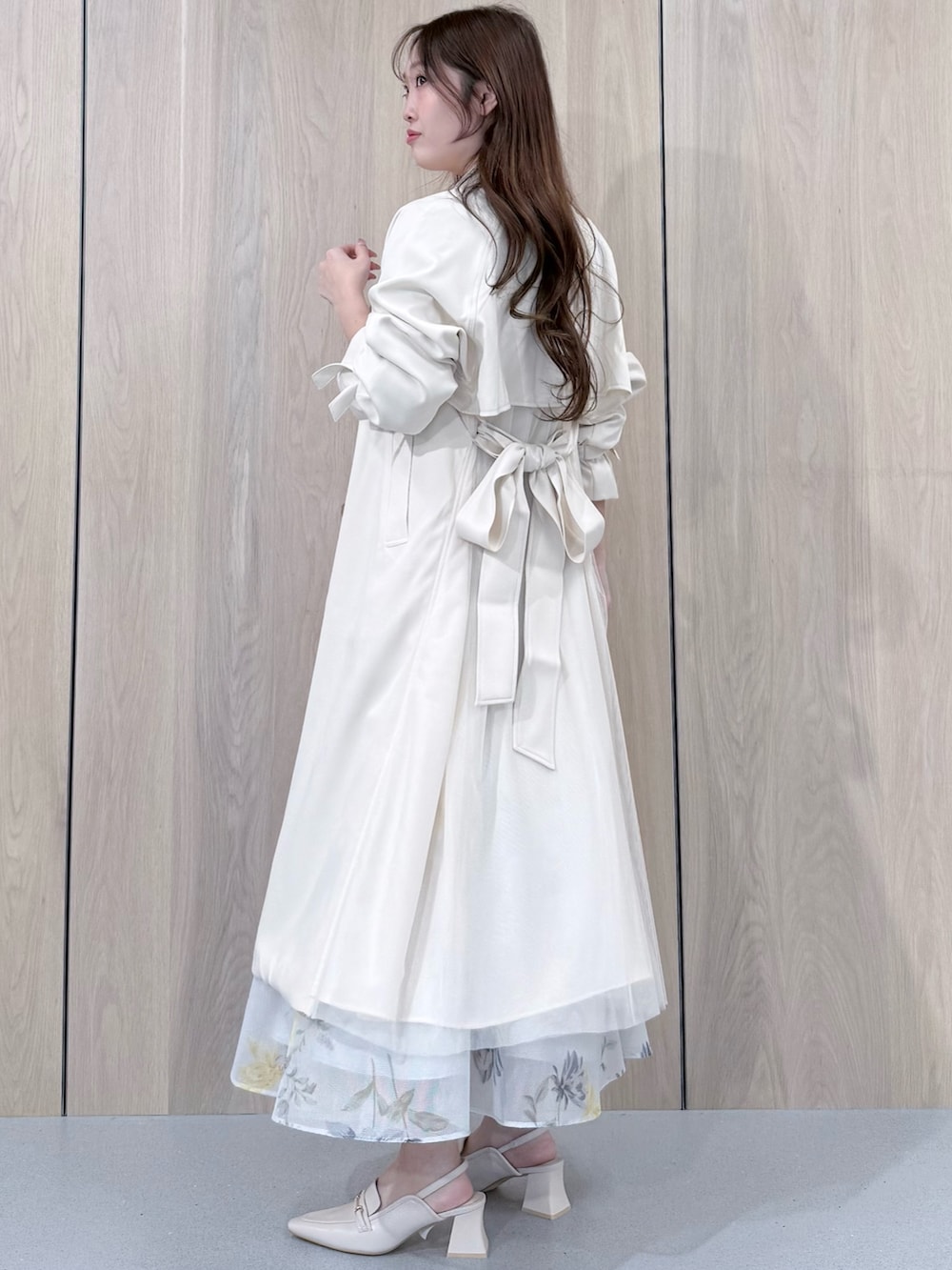 グリーン系のシャツ/ブラウス、グリーン系のスカート、ホワイト系のトレンチコートを着用したレディースの春コーディネートの2枚目の写真