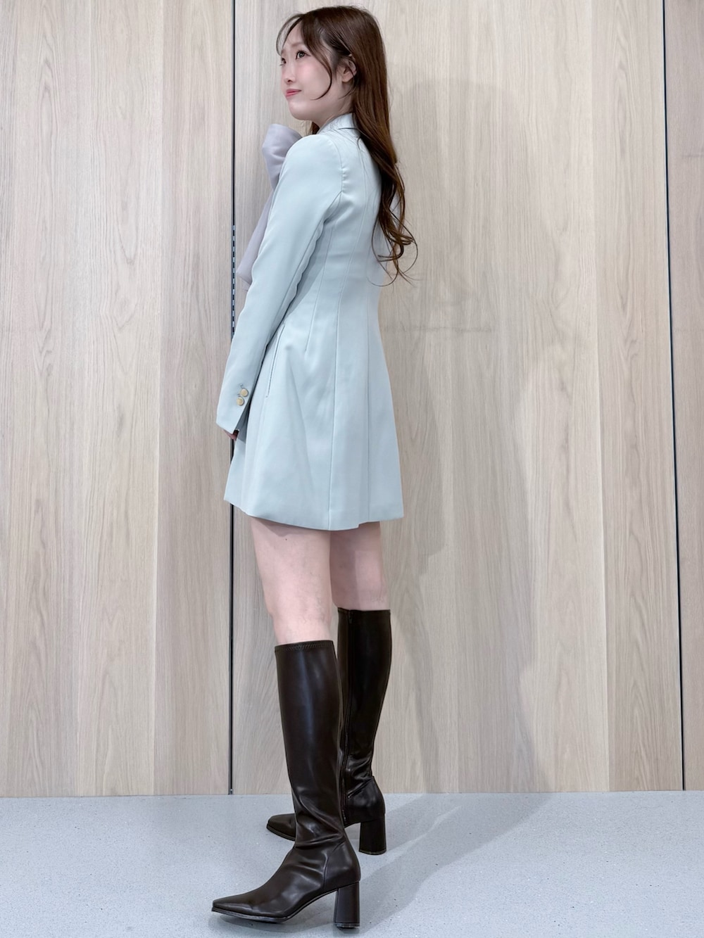 グリーン系のワンピース、ブラウン系のブーツ、グレー系のシャツ/ブラウスを着用したレディースの冬コーディネートの2枚目の写真