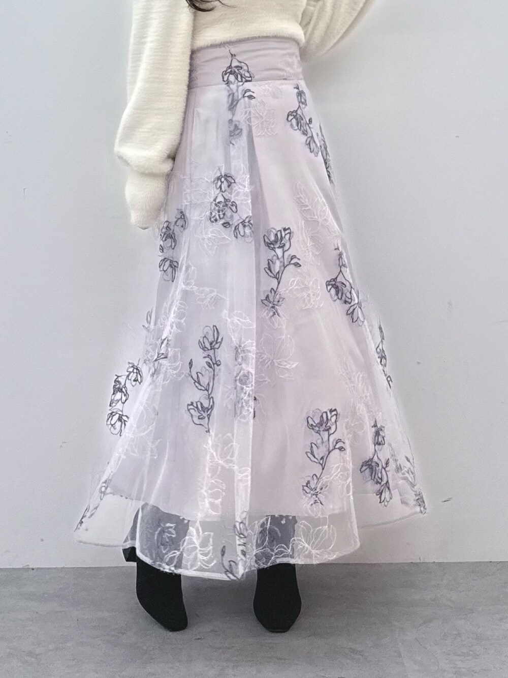 パープル系のスカート、ホワイト系のニット/セーター、ブラック系のブーツを着用したレディースの秋コーディネートの7枚目の写真